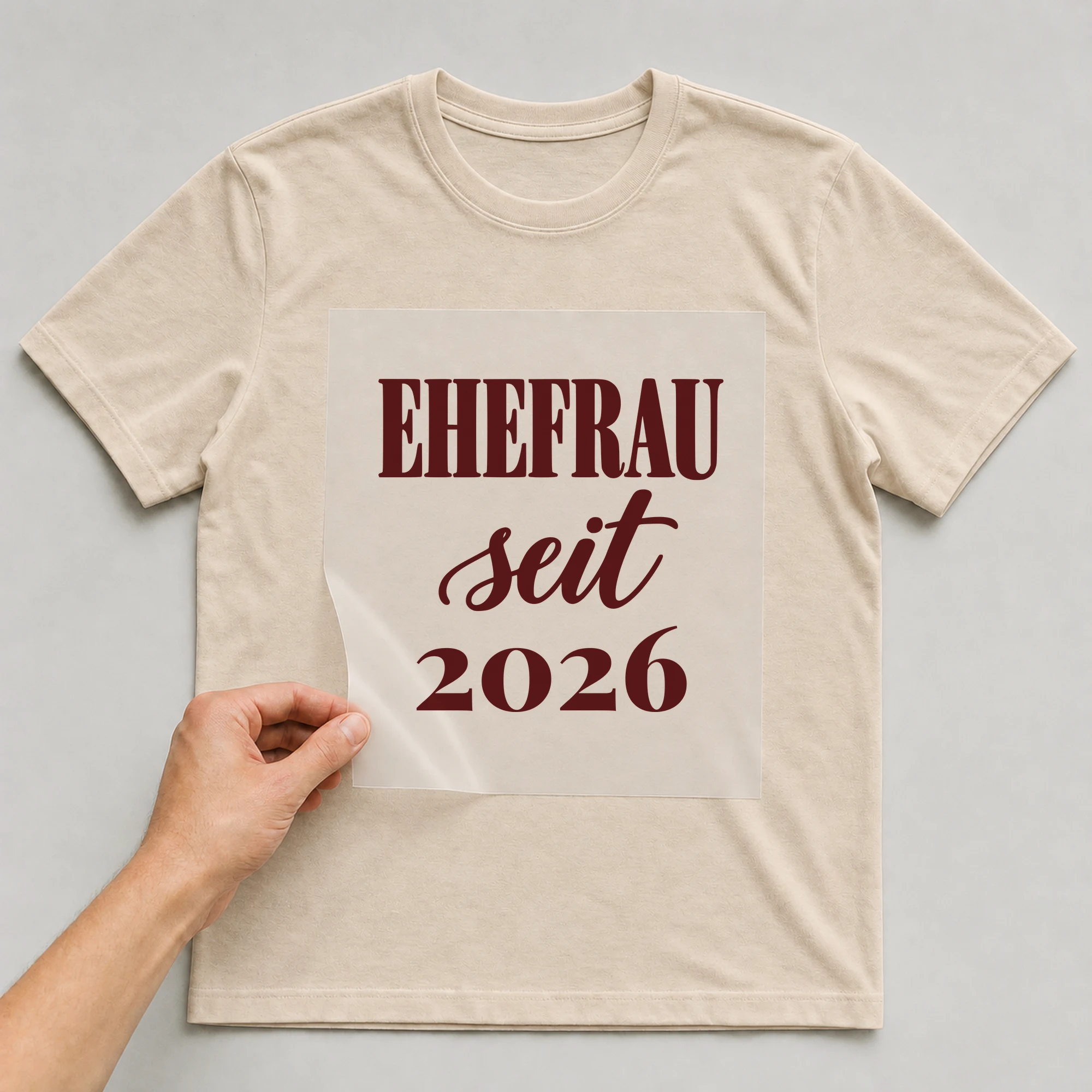 Bügelbild Ehefrau seit mit Jahr auf beigem T-Shirt, Folie wird aufgelegt