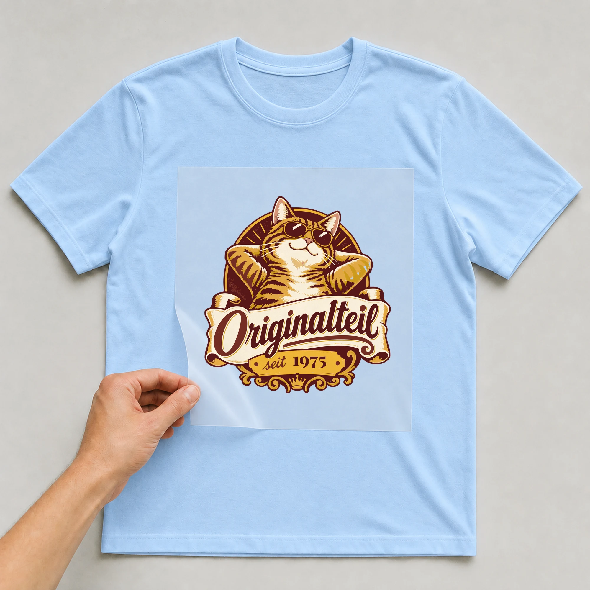 Bügelbild Originalteil mit Jahr auf hellblauem T-Shirt, Folie wird aufgelegt