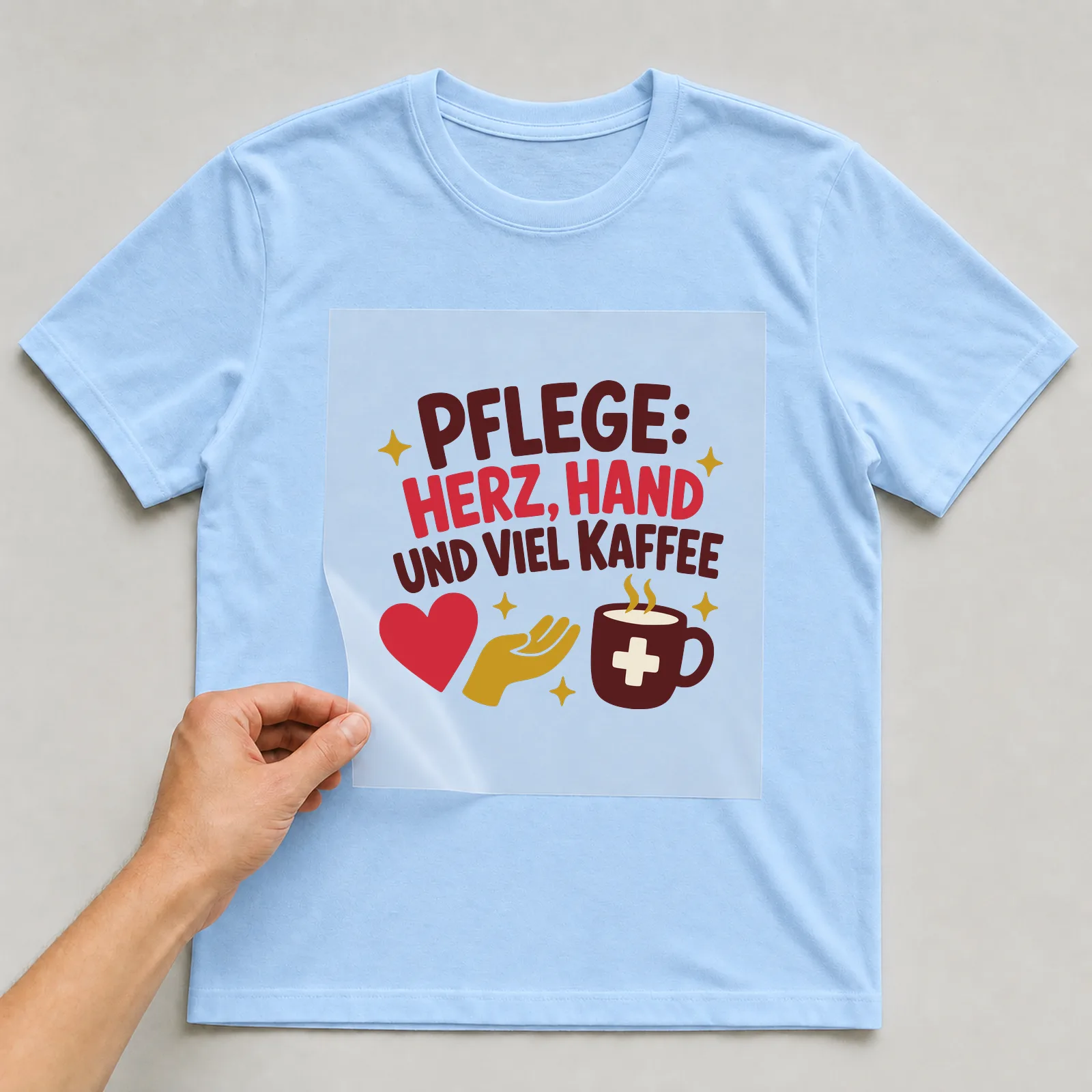 Bügelbild Pflege: Herz, Hand und viel Kaffee auf hellblauem T-Shirt, Folie wird aufgelegt