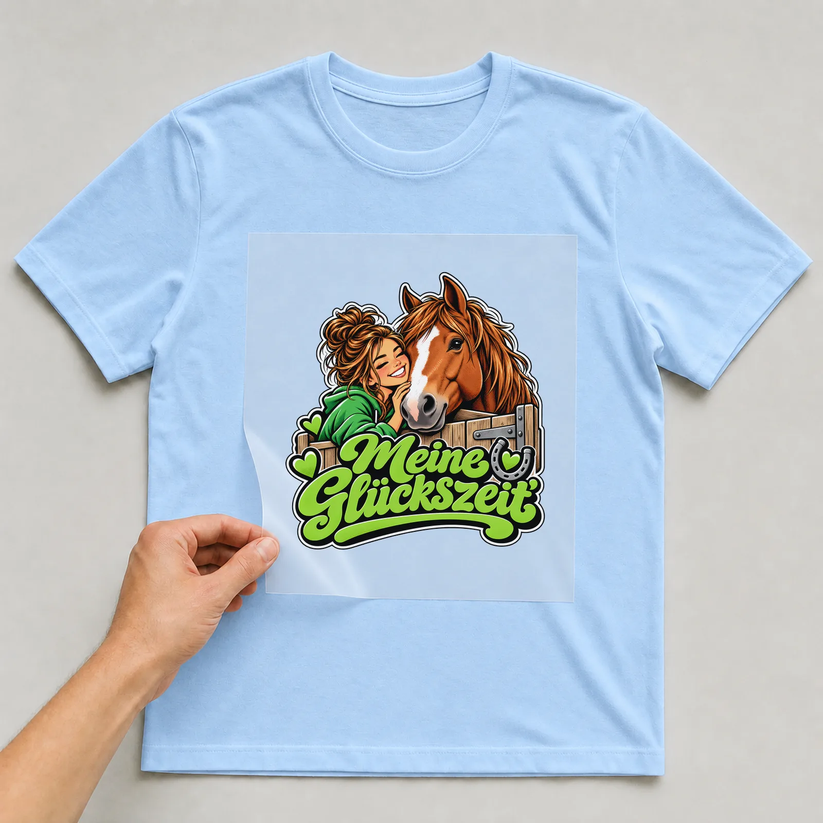 Bügelbild „Meine Glückszeit“ auf hellblauem T-Shirt, Folie wird aufgelegt