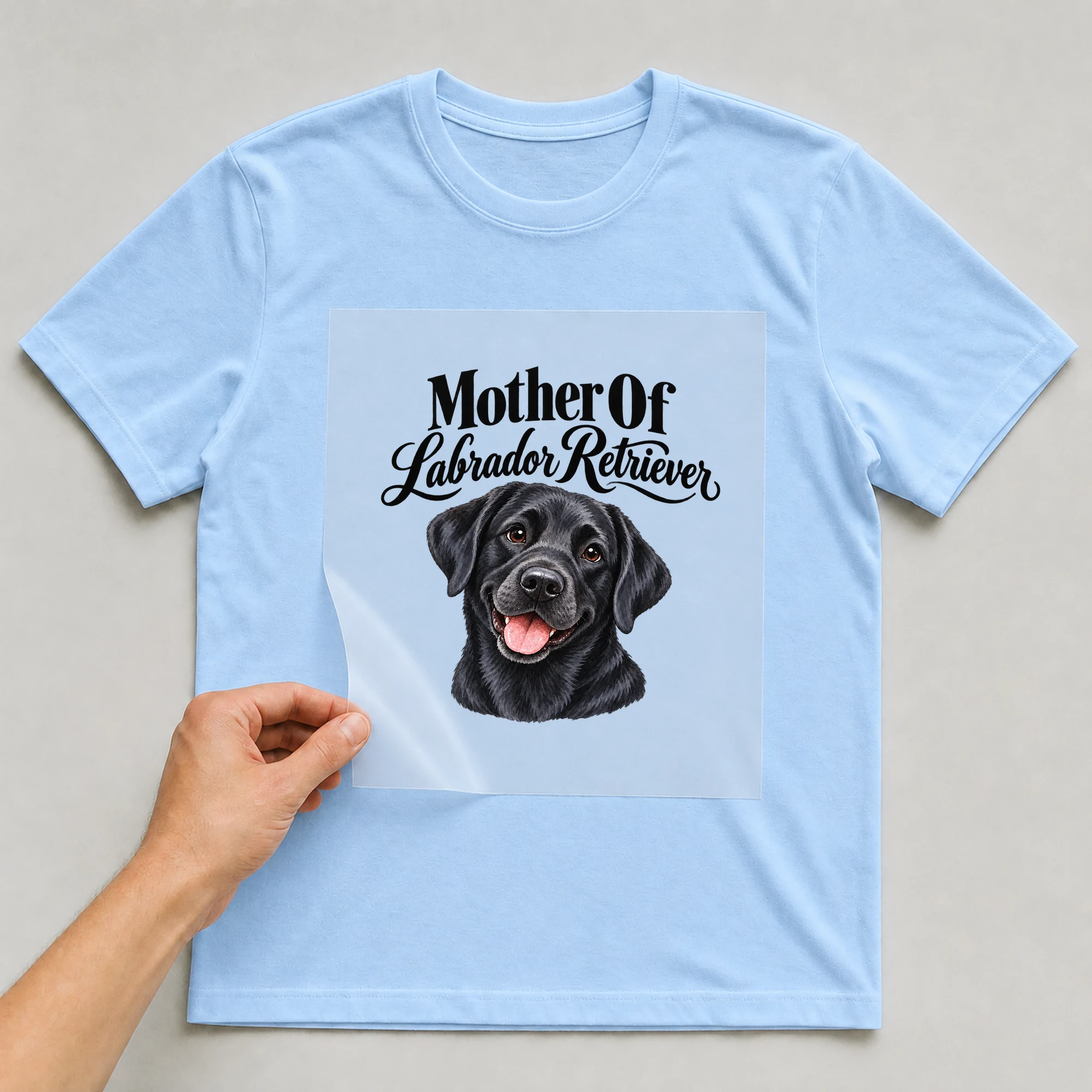 Bügelbild „Mother Of Labrador Retriever“ auf babyblauem T-Shirt, Folie wird aufgelegt