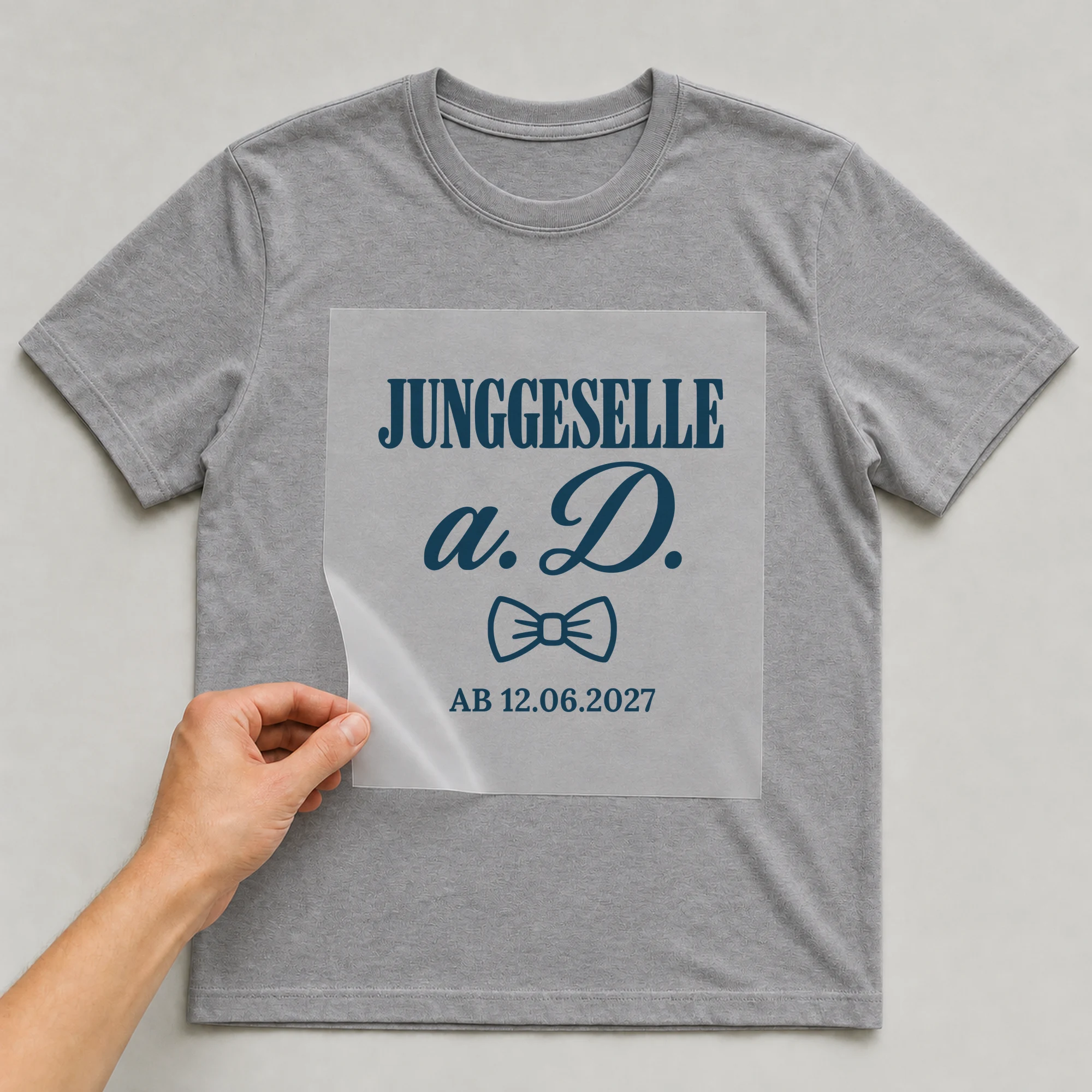 Bügelbild Junggeselle a. D. ab mit Datum auf grauem T-Shirt, Folie wird aufgelegt