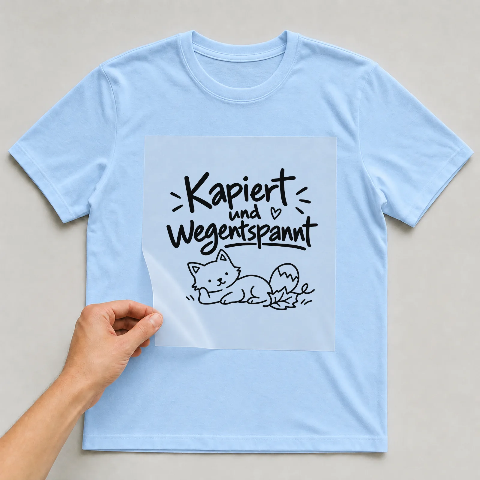Bügelbild „Kapiert und wegentspannt“ auf hellblauem T-Shirt, Folie wird aufgelegt