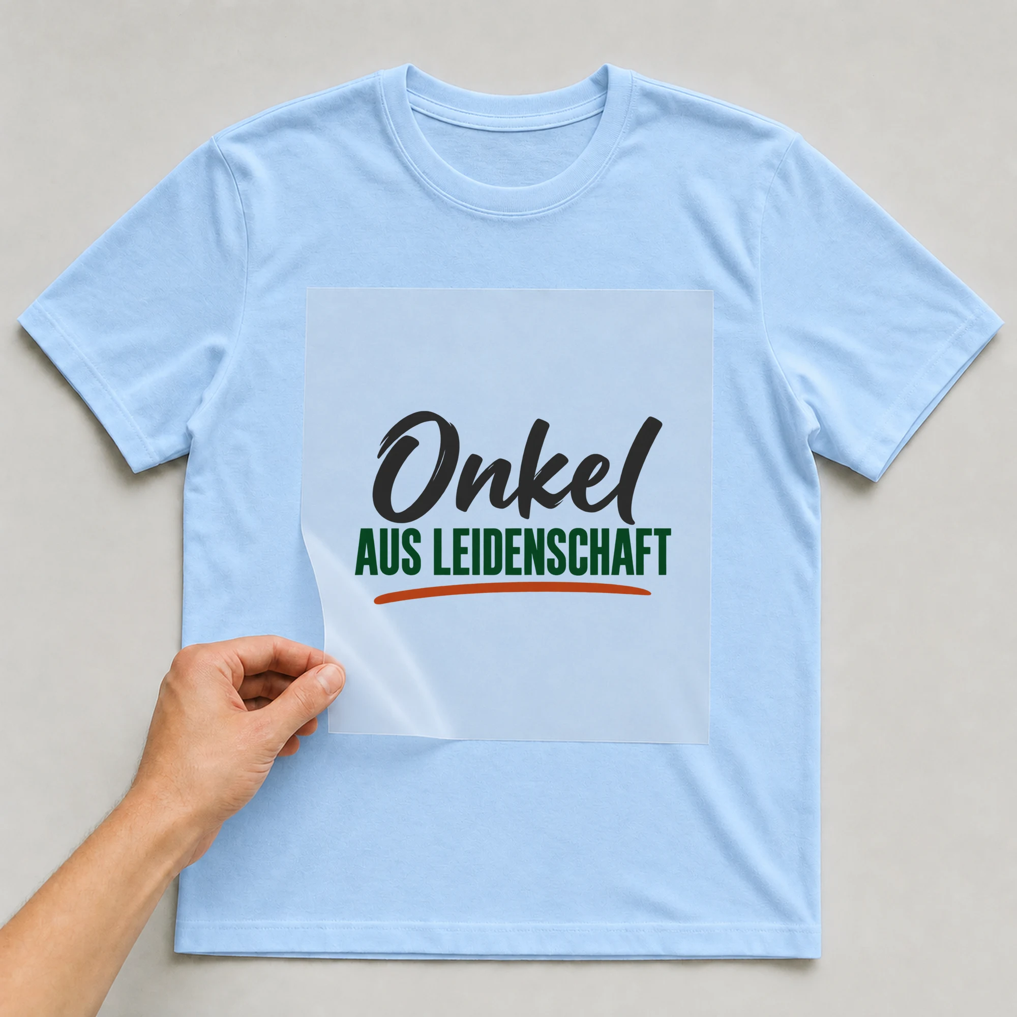 Bügelbild „Onkel aus Leidenschaft“ auf babyblauem T-Shirt, Folie wird aufgelegt