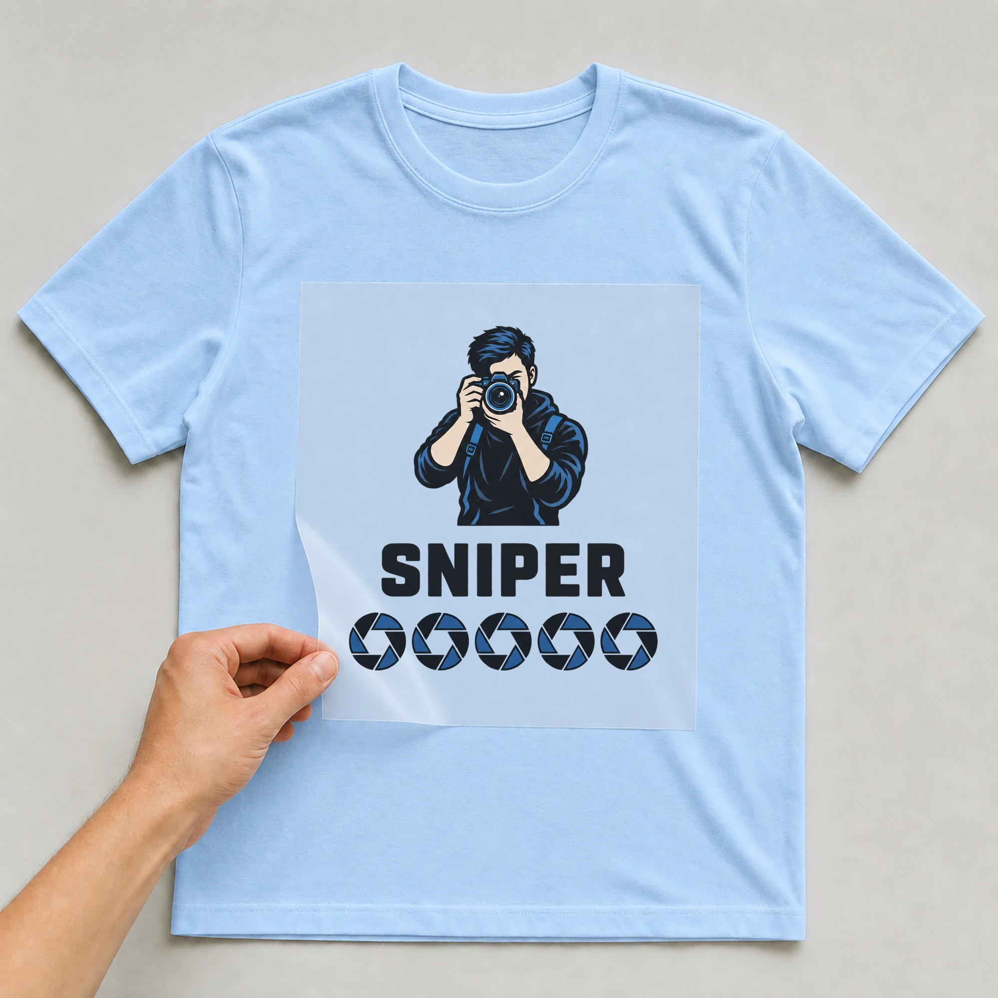 Bügelbild „SNIPER“ auf babyblauem T-Shirt, Folie wird aufgelegt