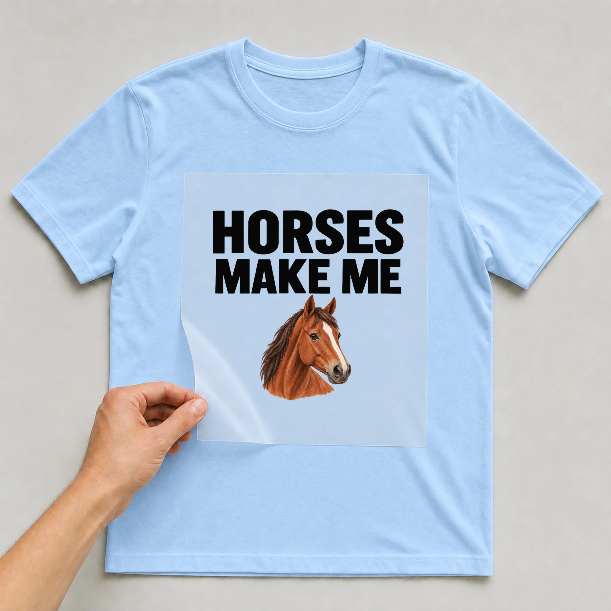 Bügelbild „Horses Make Me“ auf babyblauem T-Shirt, Folie wird aufgelegt