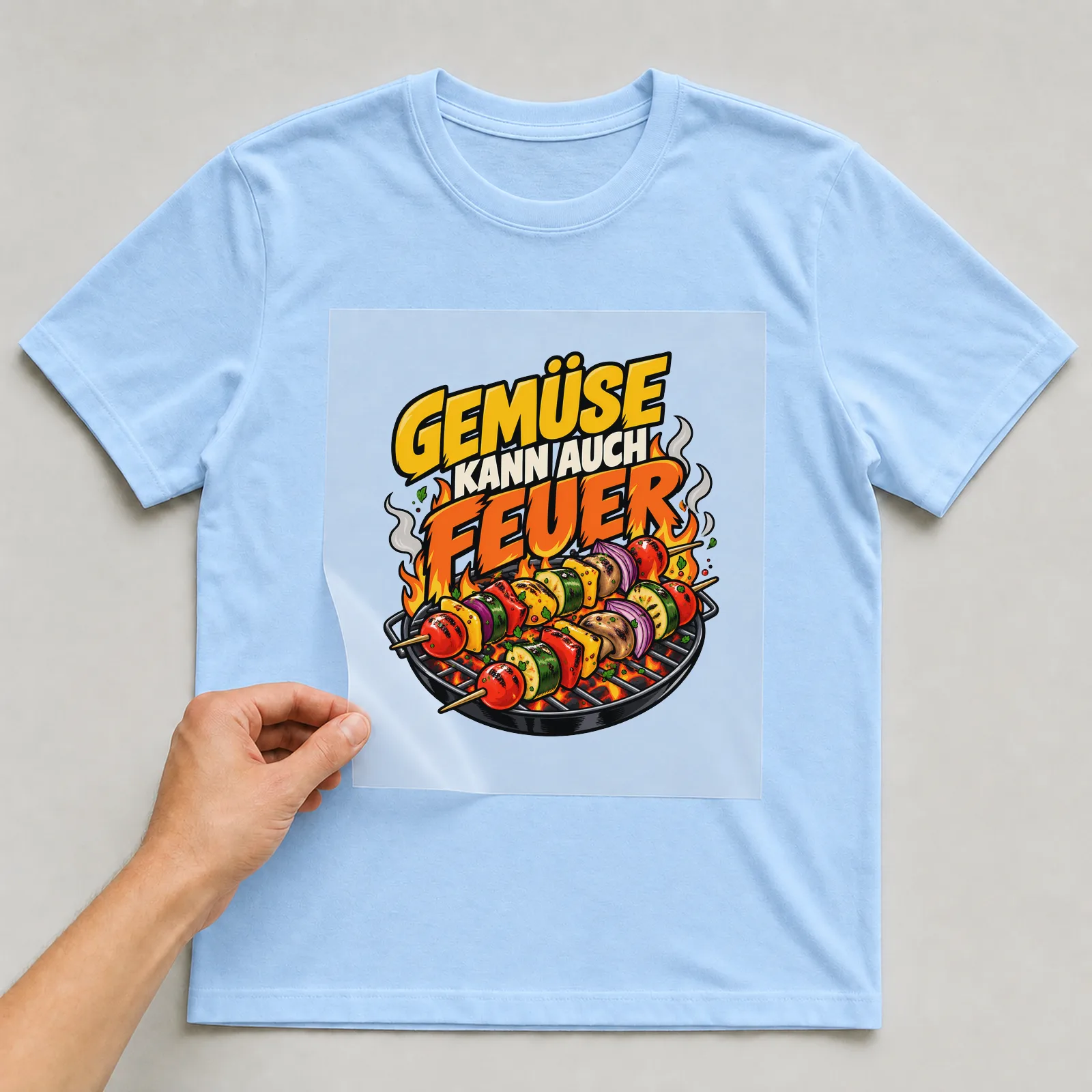 Bügelbild „Gemüse kann auch feuer“ auf hellblauem T-Shirt, Folie wird aufgelegt