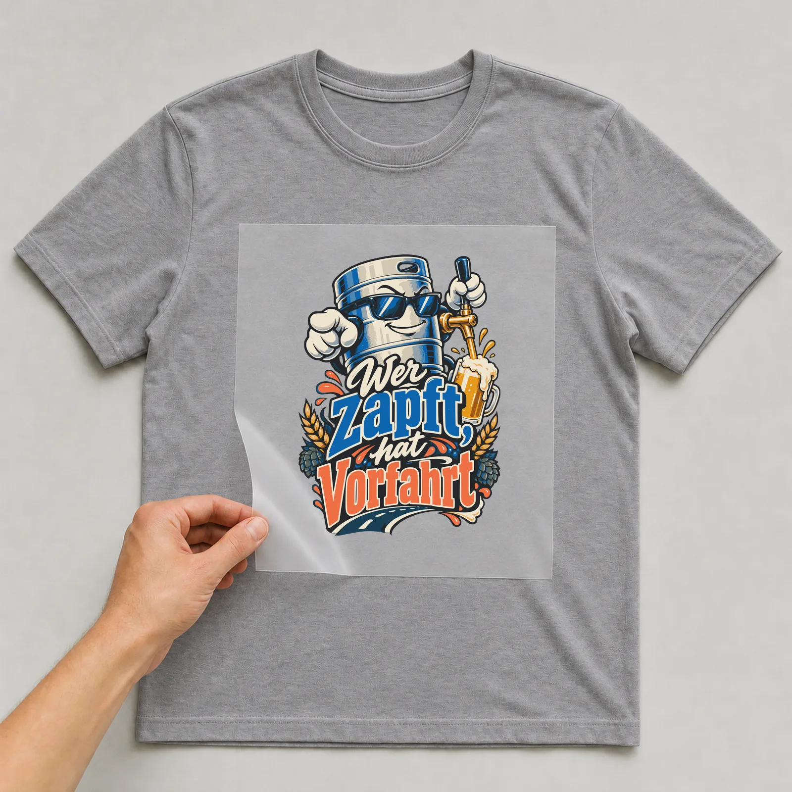 Bügelbild Wer zapft, hat Vorfahrt auf grauem T-Shirt, Folie wird aufgelegt