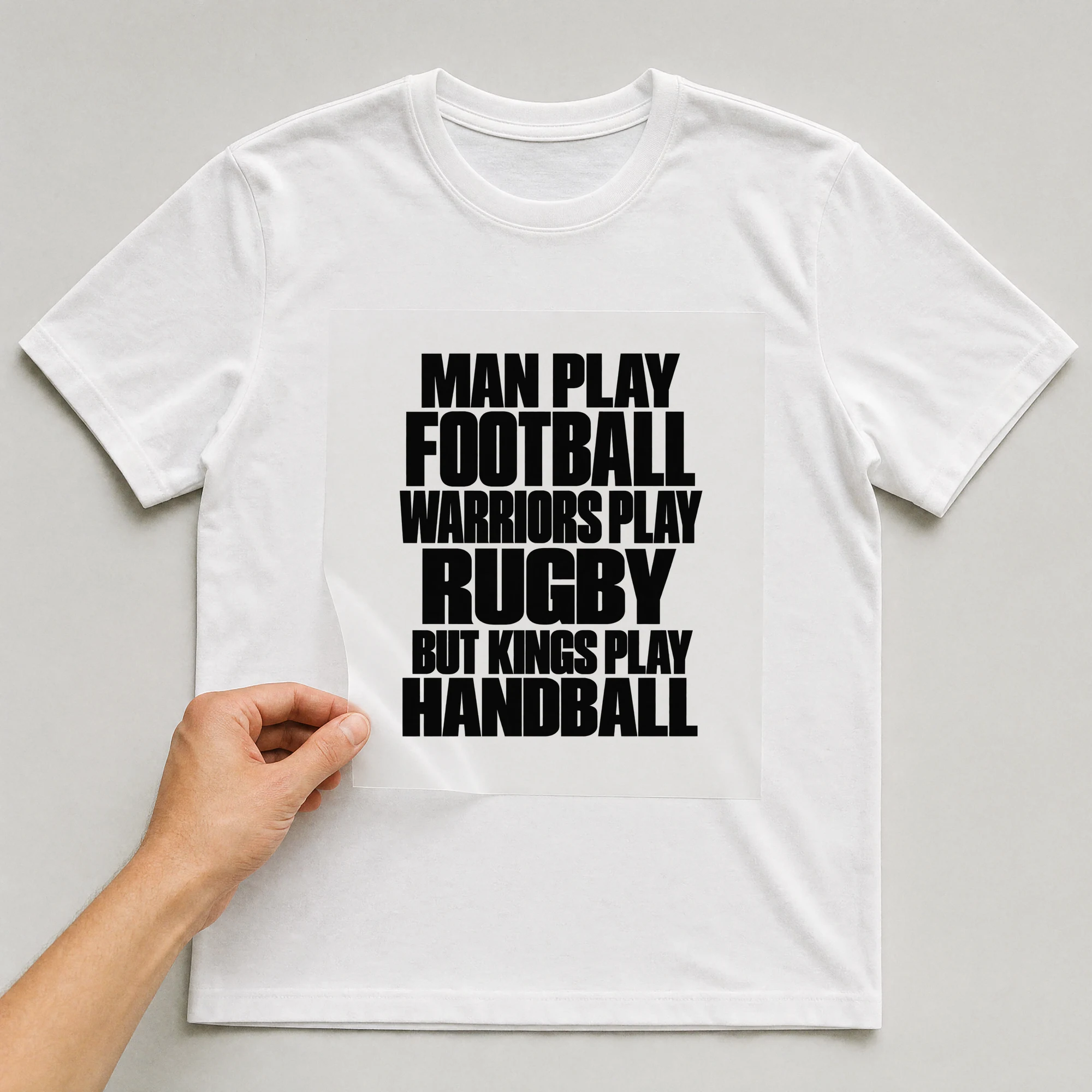 Bügelbild „Man Play Football Warriors Play Rugby But Kings Play Handball“ auf weißem T-Shirt, Folie wird aufgelegt