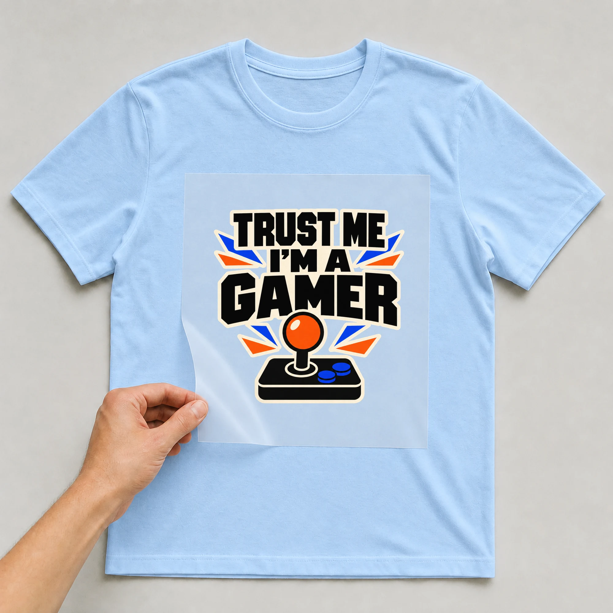 Bügelbild „Trust Me I'm A Gamer“ auf babyblauem T-Shirt, Folie wird aufgelegt