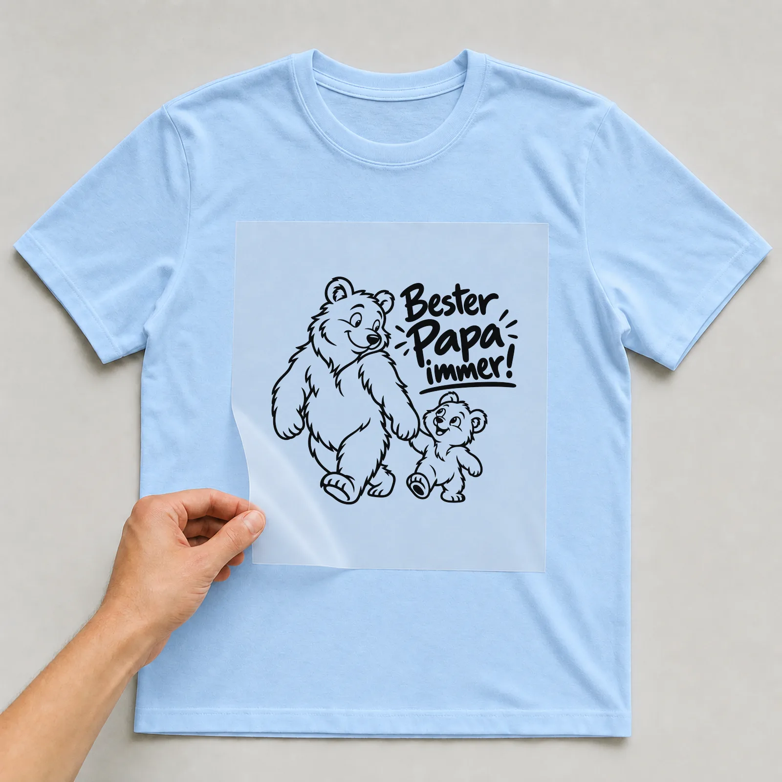 Bügelbild „Bester Papa immer!“ auf hellblauem T-Shirt, Folie wird aufgelegt
