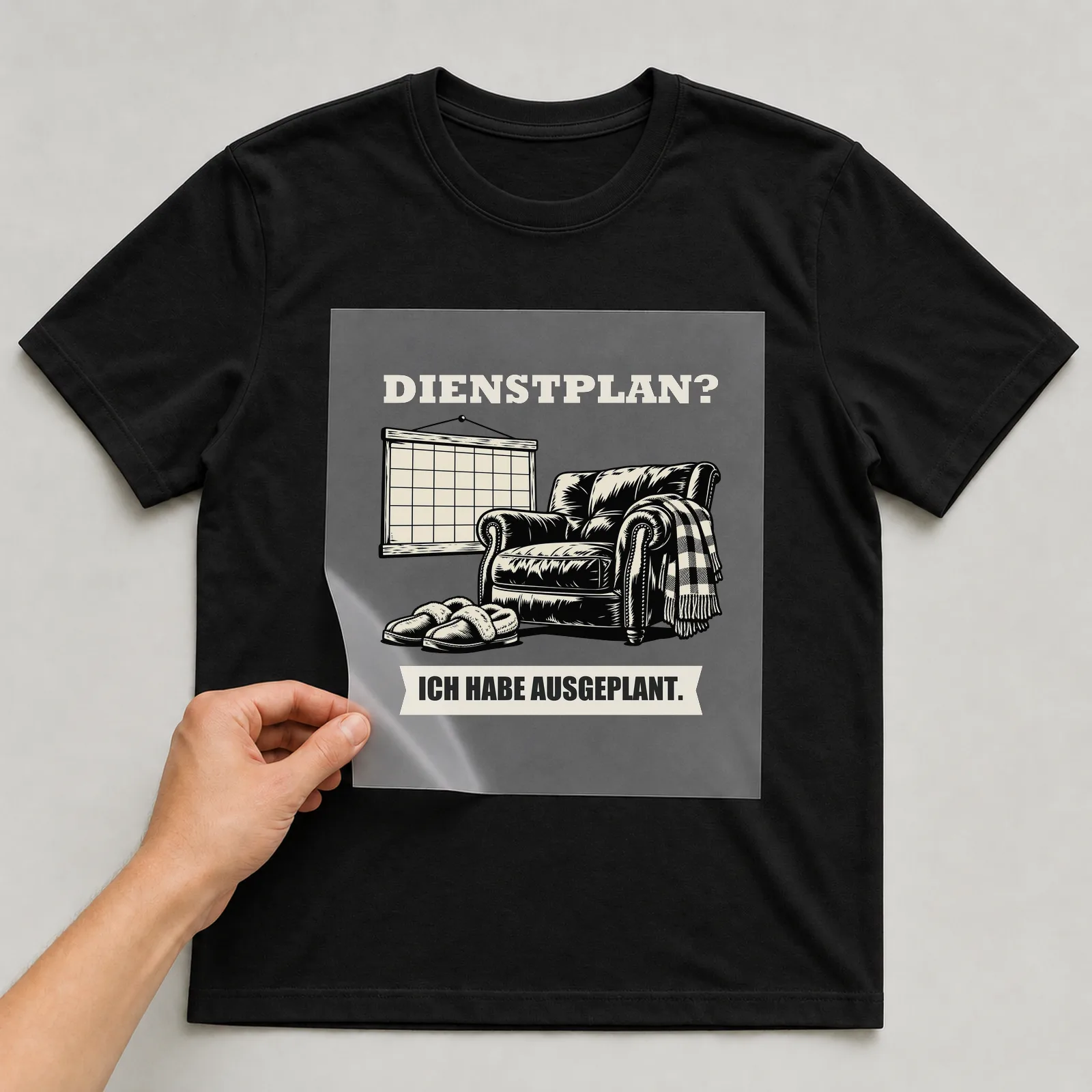 Bügelbild „Dienstplan? Ich habe Ausgeplant.“ auf schwarzem T-Shirt, Folie wird aufgelegt