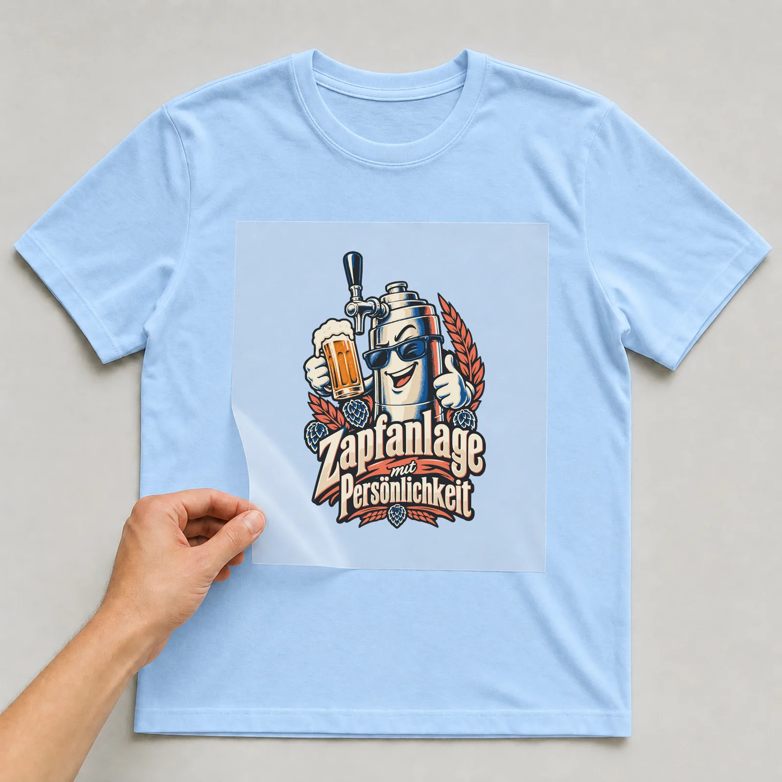 Bügelbild Zapfanlage mit Persönlichkeit auf hellblauem T-Shirt, Folie wird aufgelegt