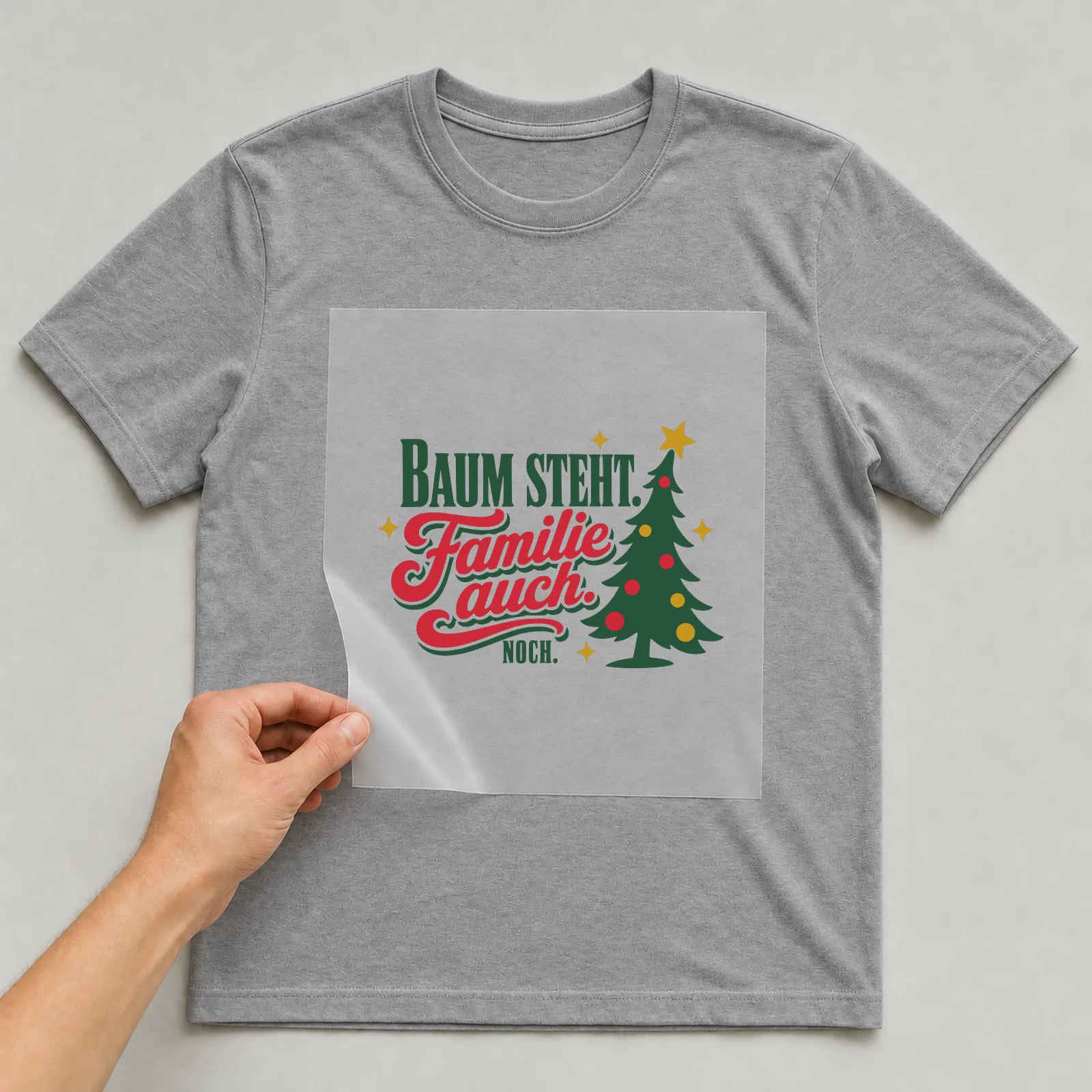 Bügelbild Baum steht. Familie auch. Noch. auf grauem T-Shirt, Folie wird aufgelegt