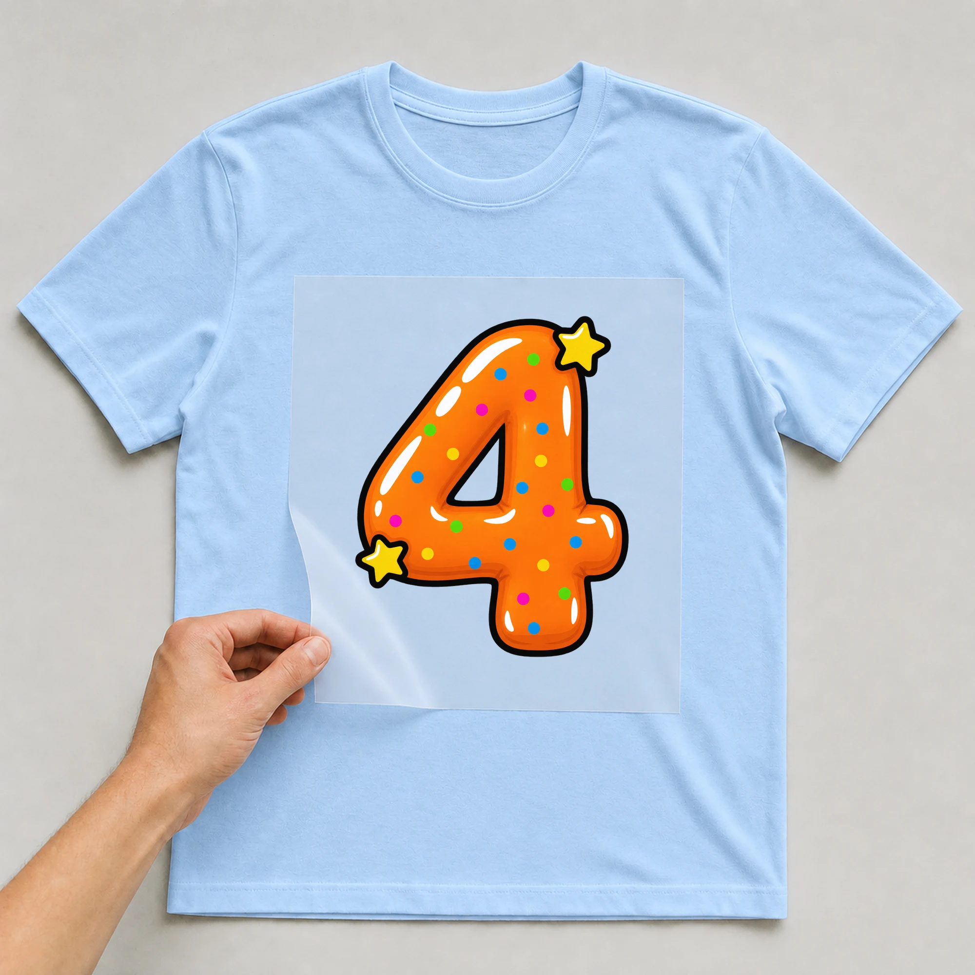 Bügelbild „Zahl 4 im Comic-Ballon-Stil“ auf babyblauem T-Shirt, Folie wird aufgelegt
