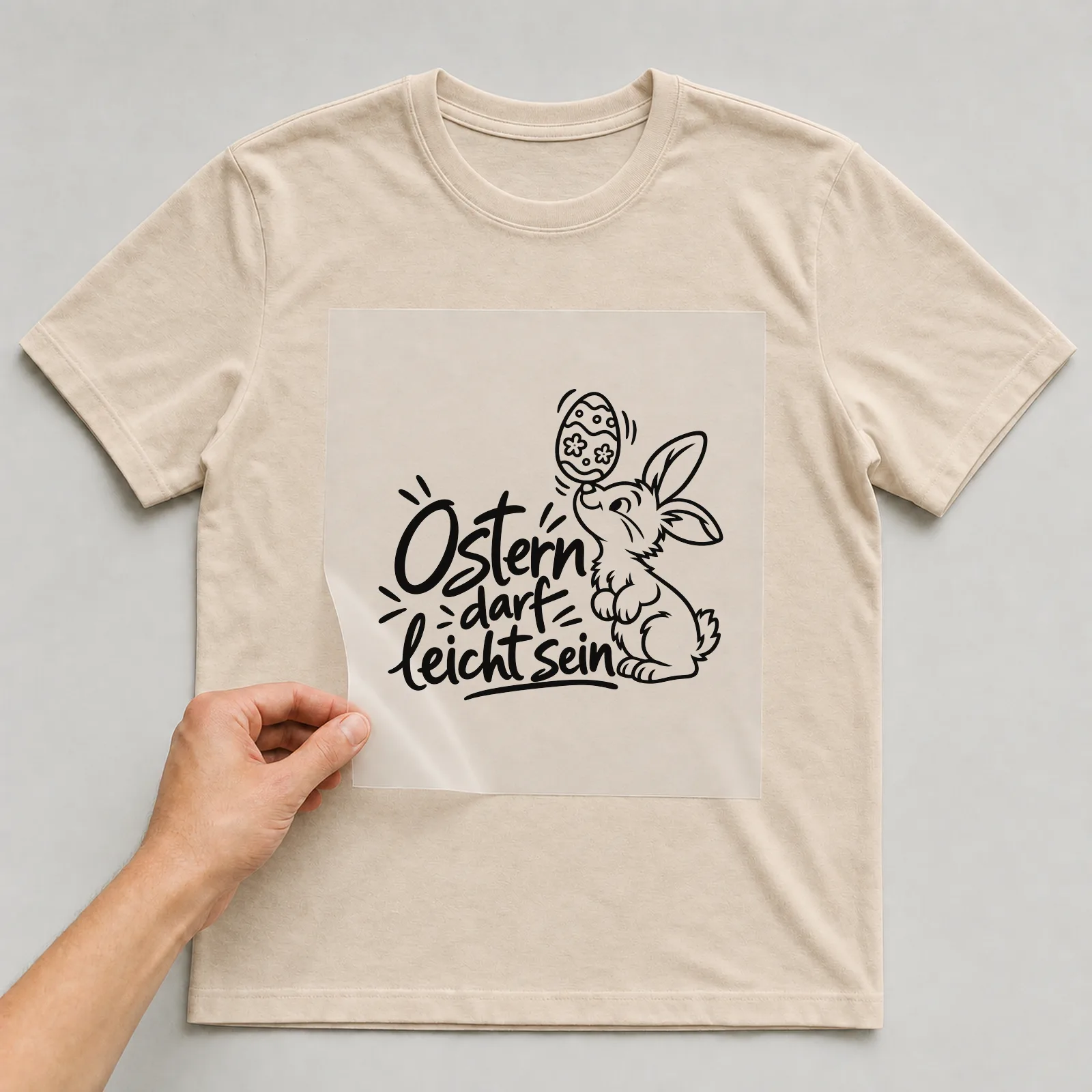 Bügelbild „Ostern darf leicht sein“ auf beigem T-Shirt, Folie wird aufgelegt