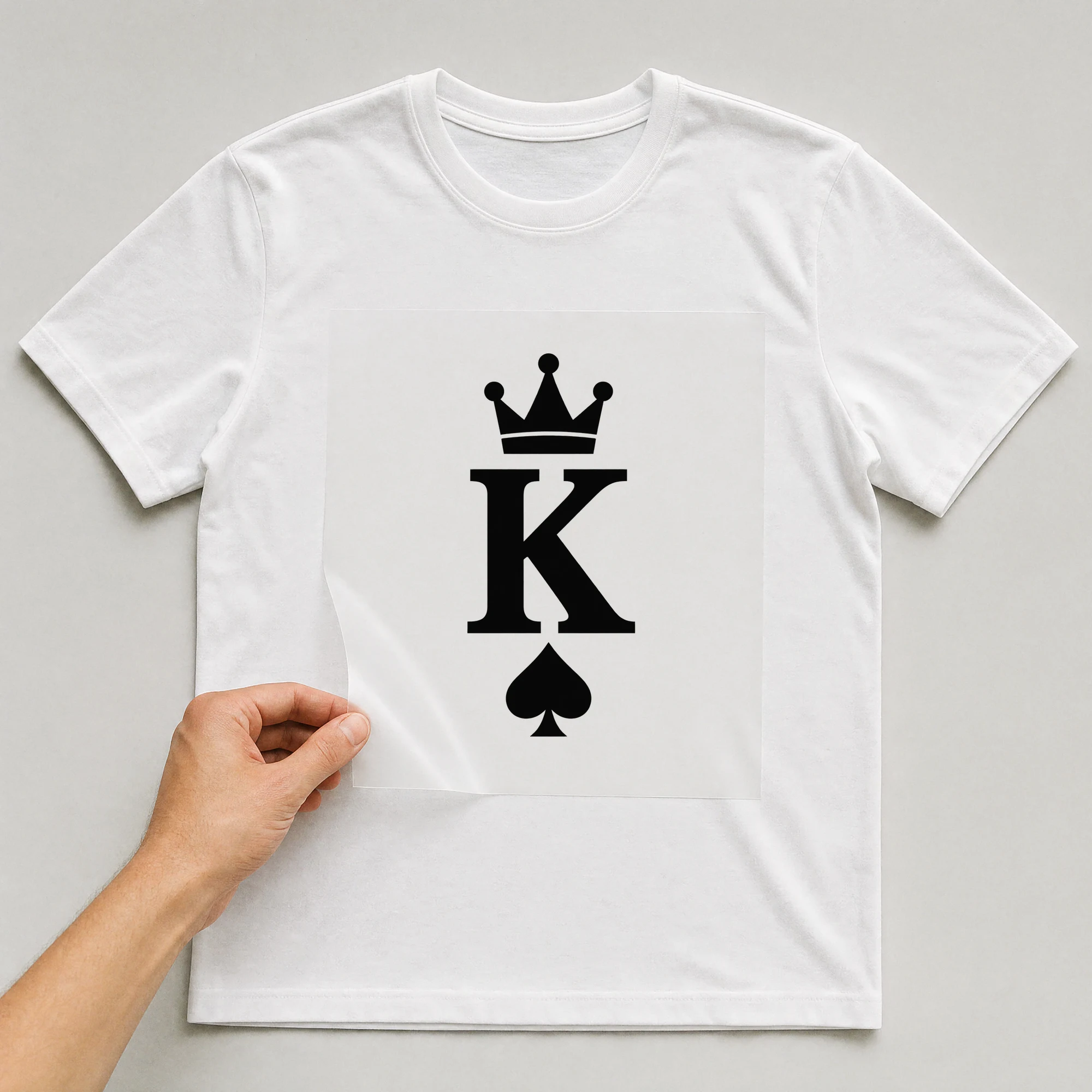 Bügelbild „K“ auf weißem T-Shirt, Folie wird aufgelegt