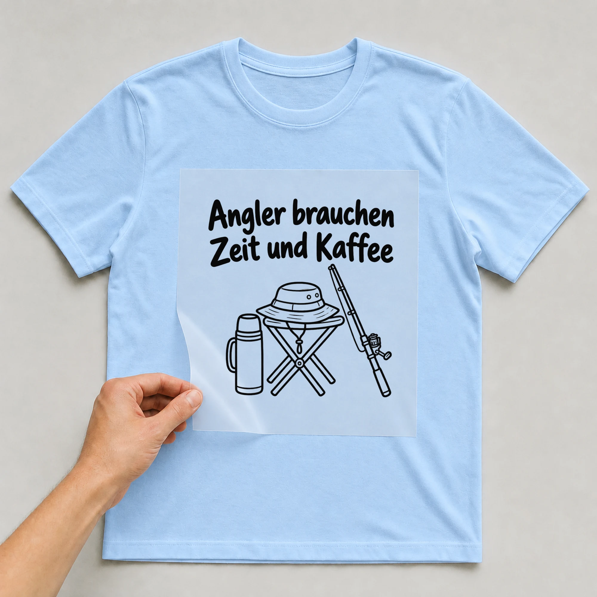 Bügelbild „Angler brauchen Zeit und Kaffee“ auf babyblauem T-Shirt, Folie wird aufgelegt