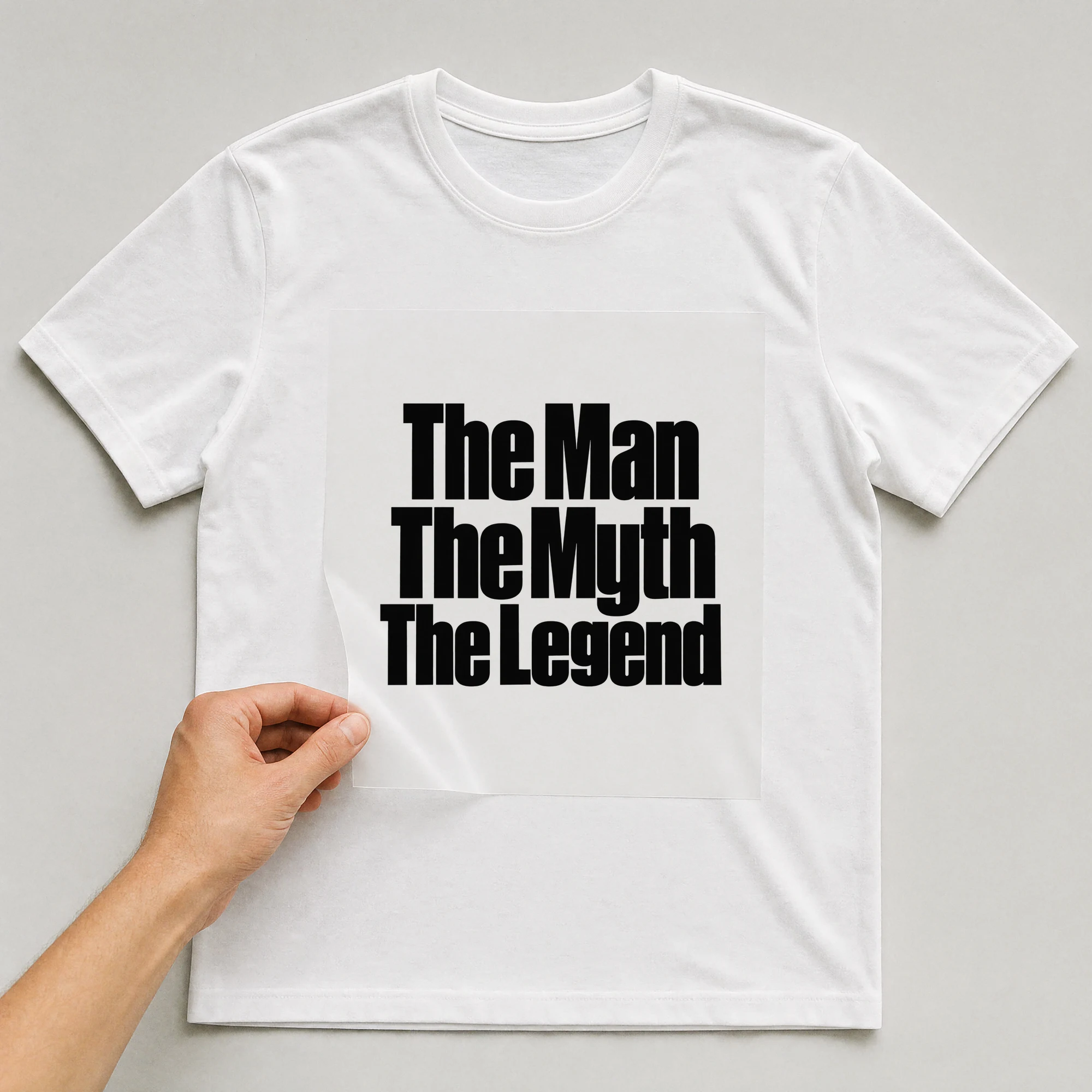 Bügelbild „The Man The Myth The Legend“ auf weißem T-Shirt, Folie wird aufgelegt