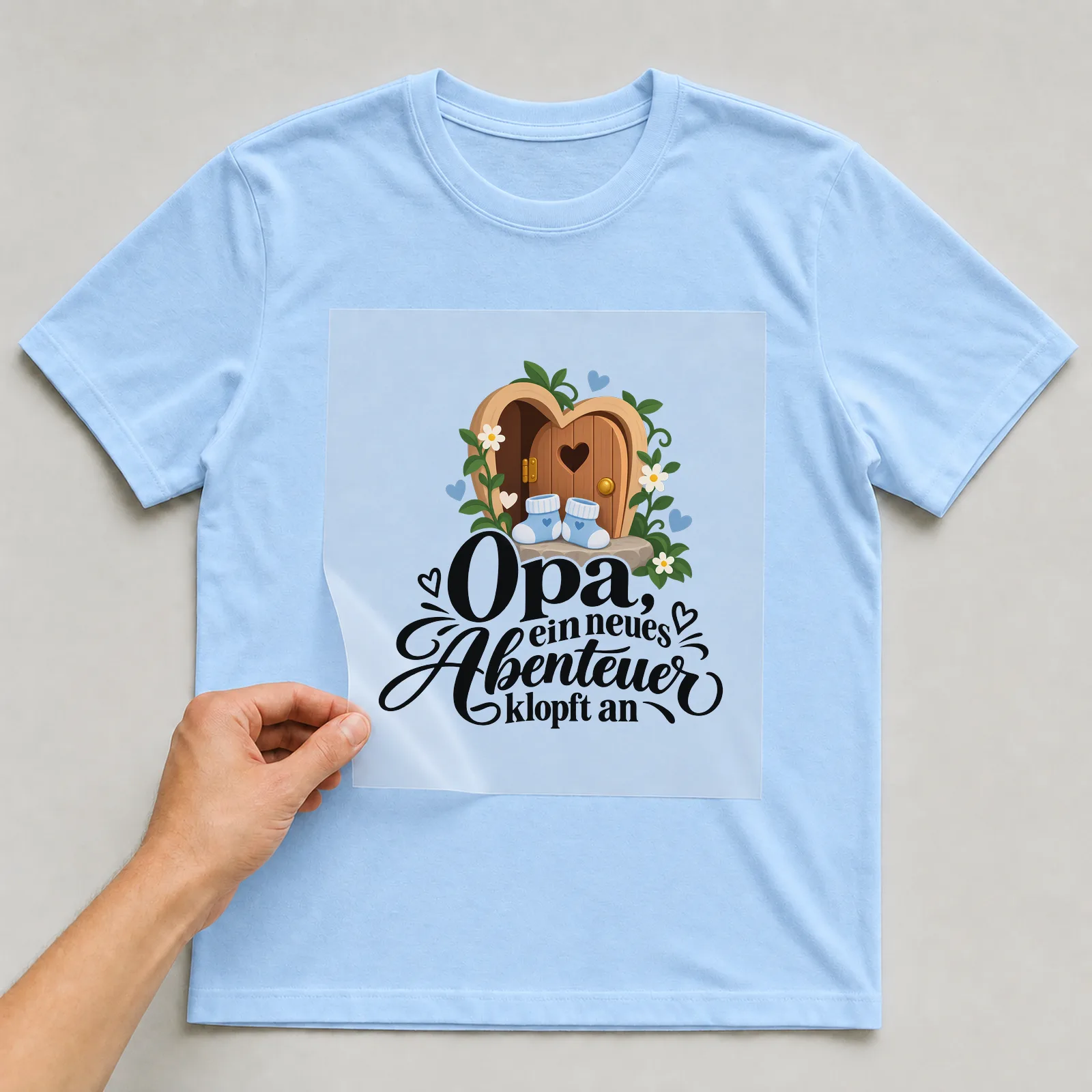 Bügelbild „Opa, ein neues Abenteuer klopft an“ auf hellblauem T-Shirt, Folie wird aufgelegt