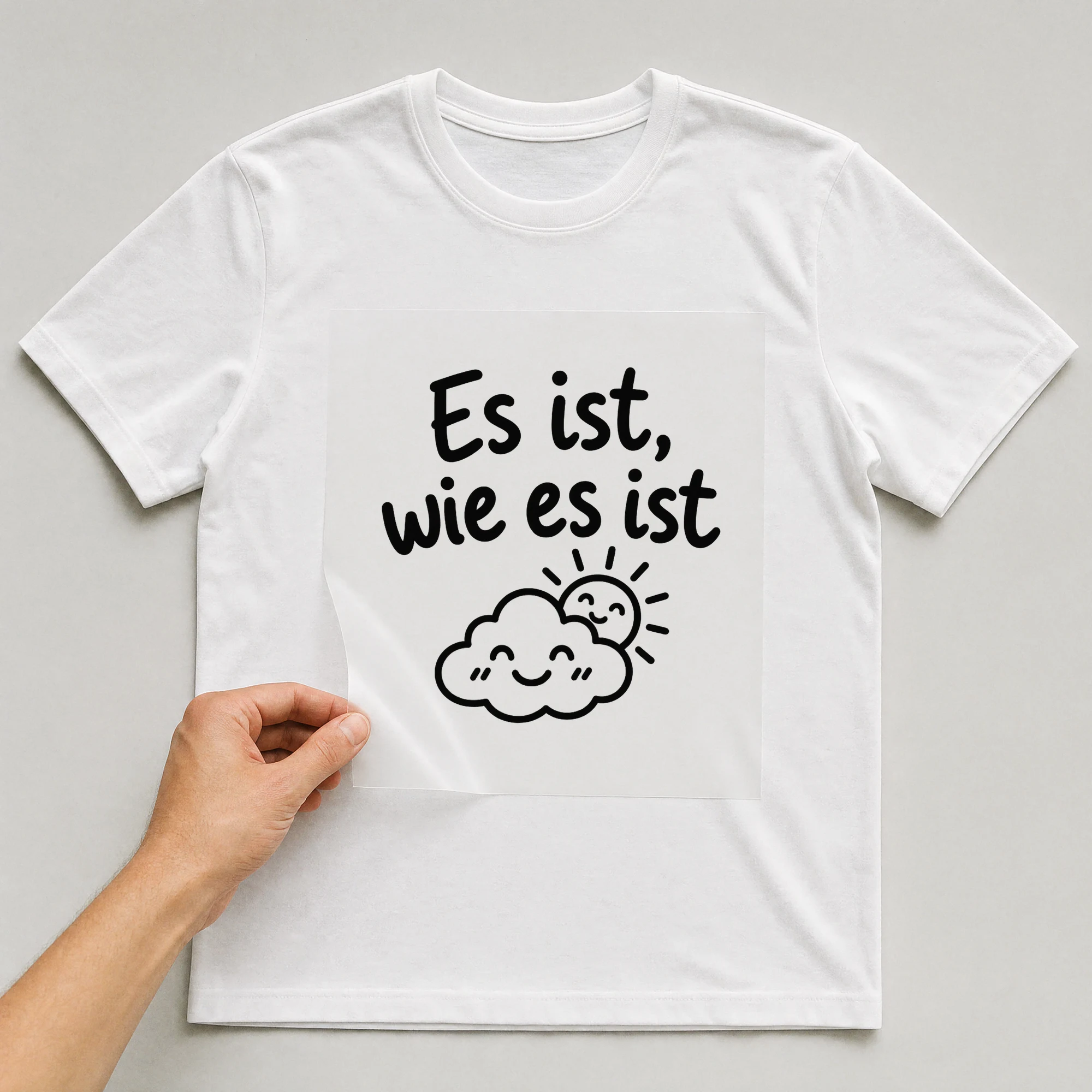 Bügelbild „Es ist, wie es ist“ auf weißem T-Shirt, Folie wird aufgelegt