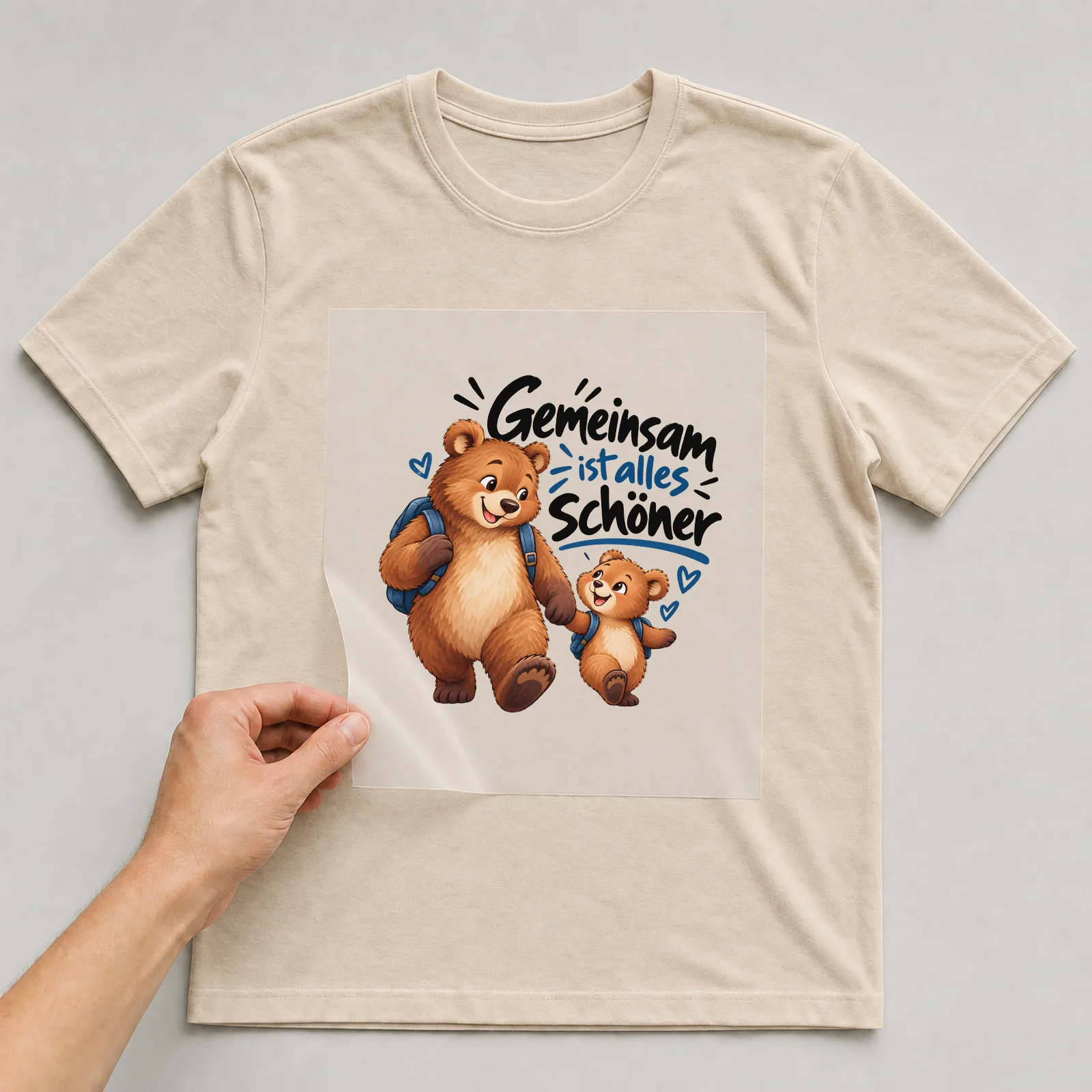 Bügelbild „Gemeinsam ist alles schöner“ auf beigem T-Shirt, Folie wird aufgelegt
