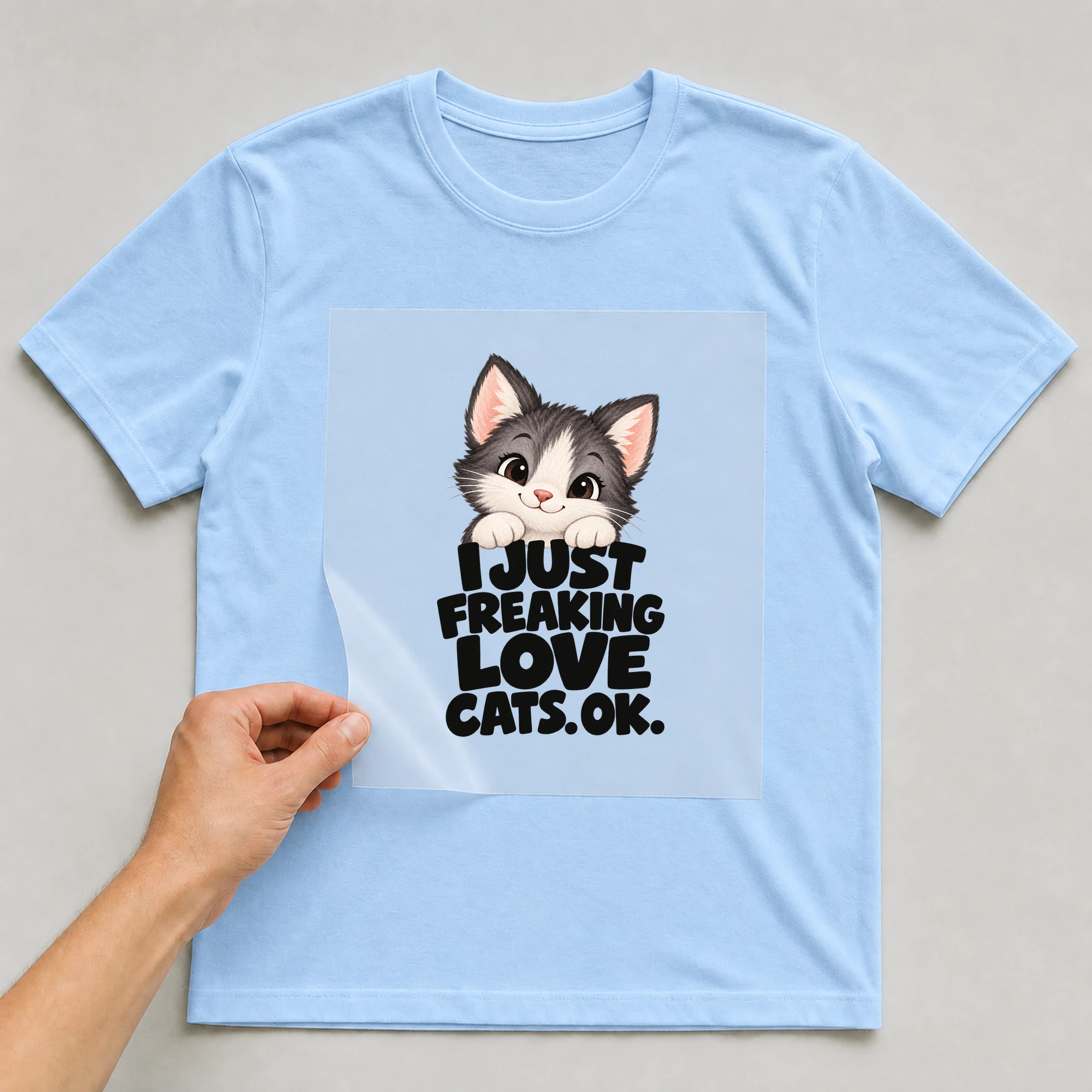 Bügelbild „I Just Freaking Love Cats. Ok.“ auf babyblauem T-Shirt, Folie wird aufgelegt