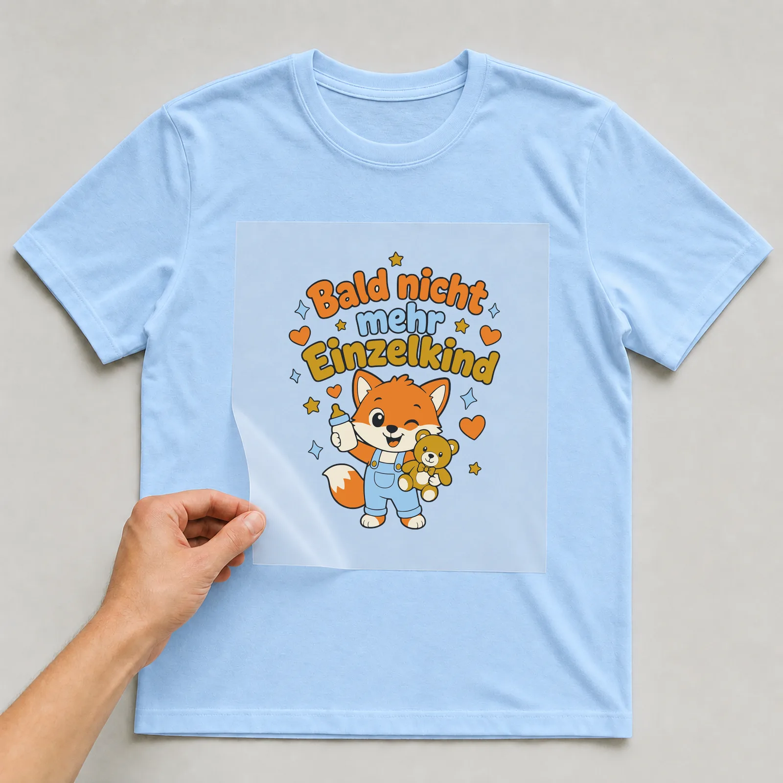 Bügelbild Bald nicht mehr Einzelkind auf hellblauem T-Shirt, Folie wird aufgelegt