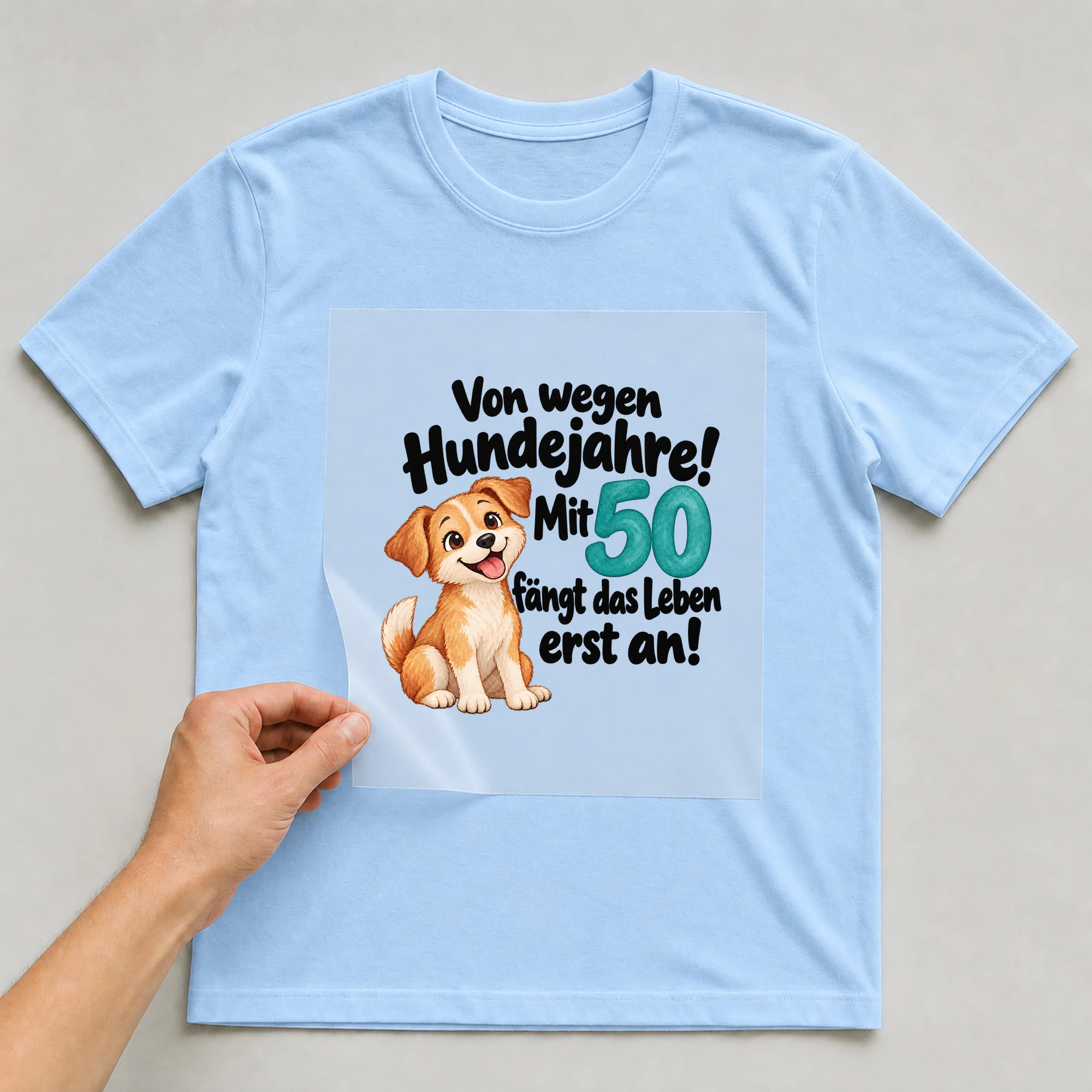Bügelbild „Von wegen Hundejahre! Mit 50 fängt das Leben erst an!“ auf babyblauem T-Shirt, Folie wird aufgelegt