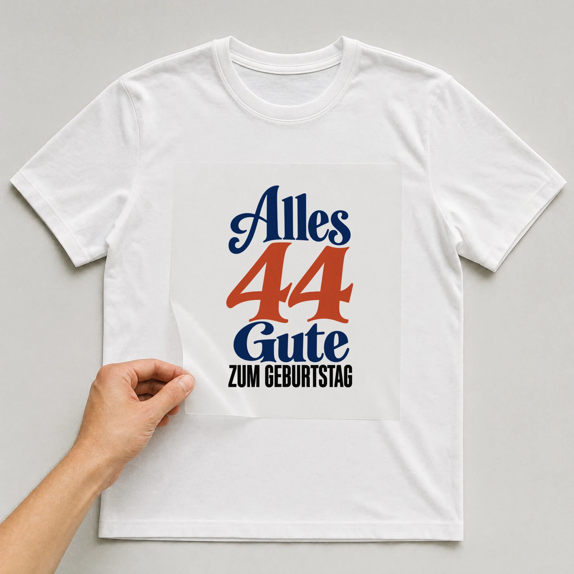 Bügelbild „Alles 44 Gute zum Geburtstag“ auf weißem T-Shirt, Folie wird aufgelegt
