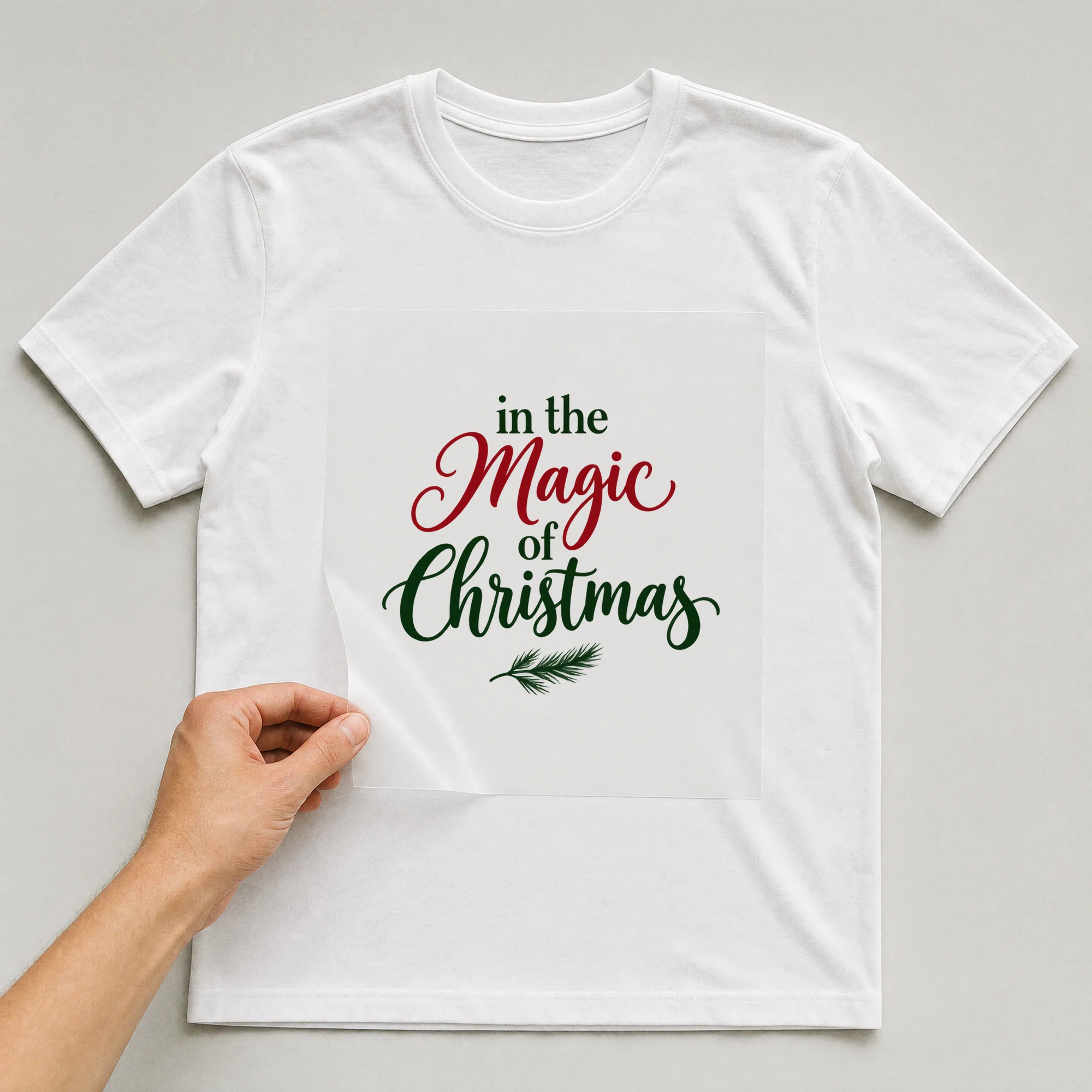 Bügelbild „in the Magic of Christmas“ auf weißem T-Shirt, Folie wird aufgelegt