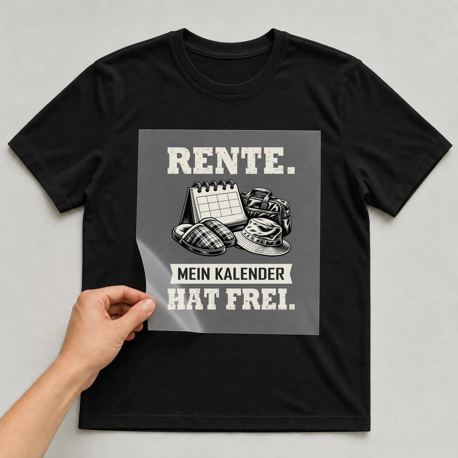 Bügelbild „Rente. Mein Kalender hat frei.“ auf schwarzem T-Shirt, Folie wird aufgelegt