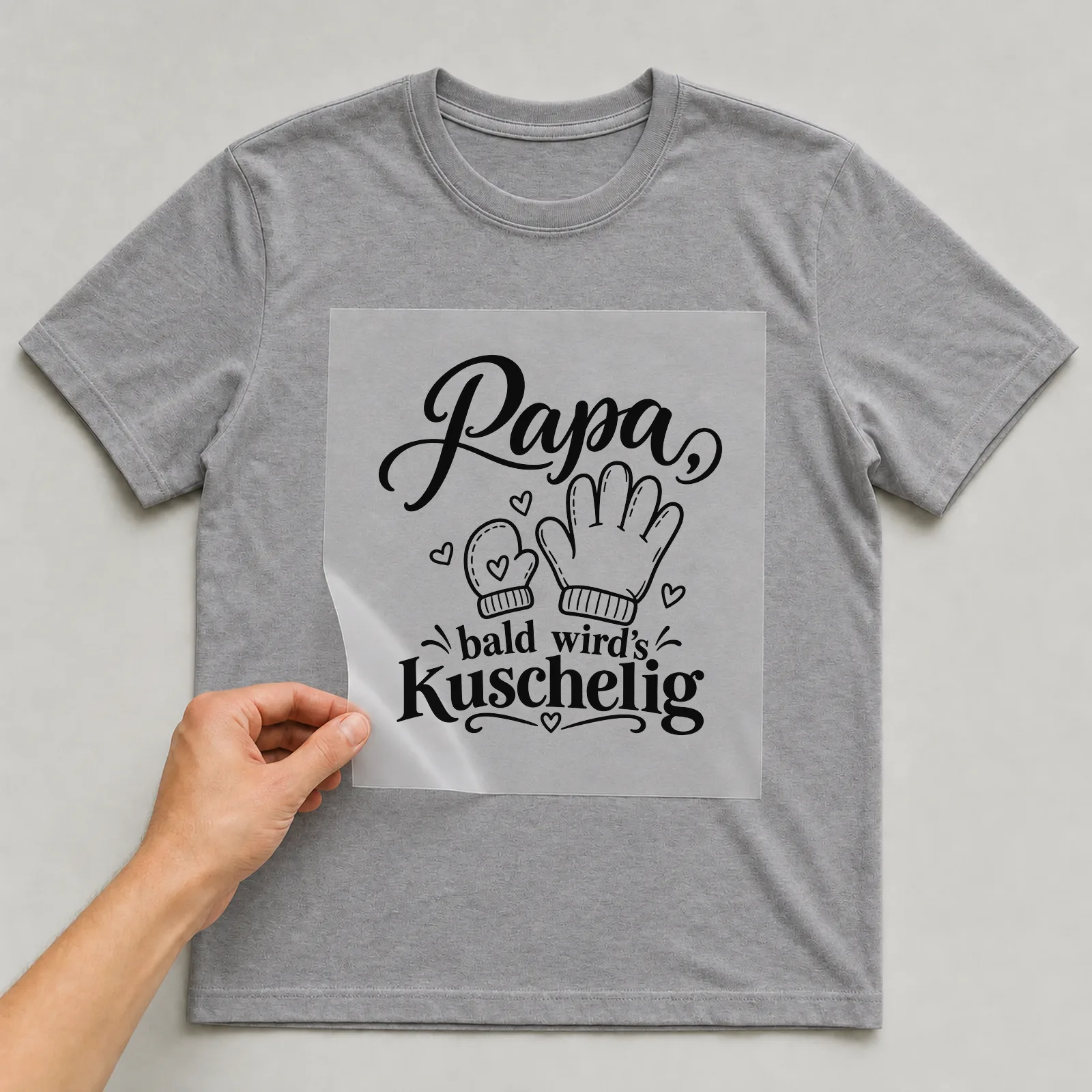 Bügelbild „Papa, bald wird’s kuschelig“ auf grauem T-Shirt, Folie wird aufgelegt