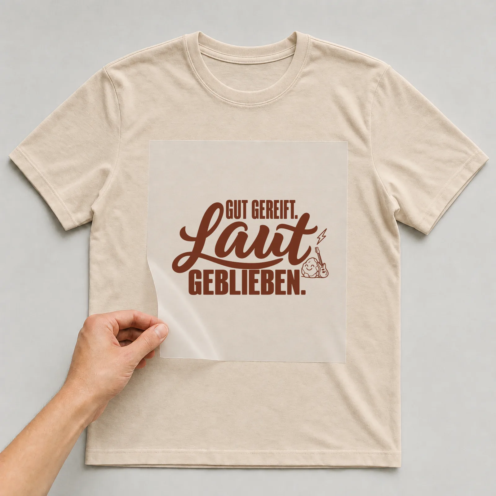 Bügelbild „Gut gereift. Laut geblieben.“ (Schrift Konturen, Nr. 2) auf beigem T-Shirt, Folie wird aufgelegt