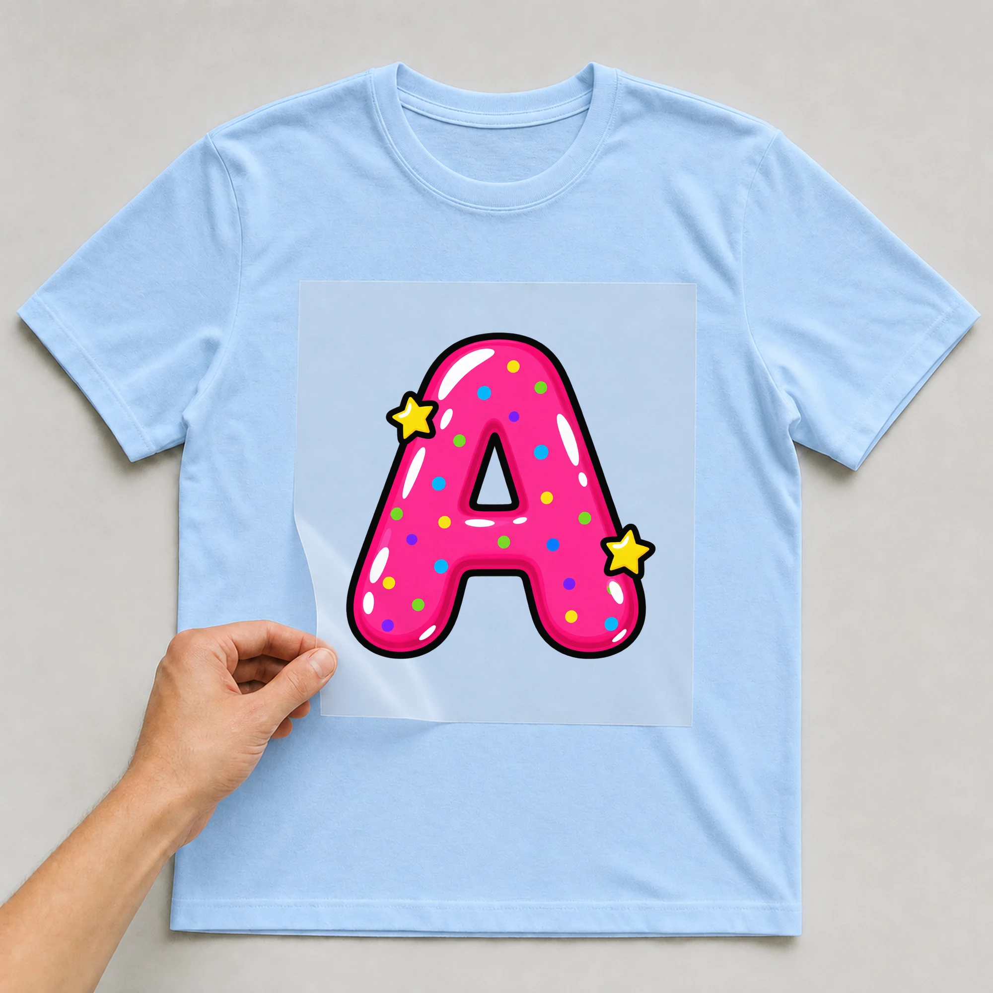 Bügelbild „Buchstabe A im Comic-Ballon-Stil“ auf babyblauem T-Shirt, Folie wird aufgelegt