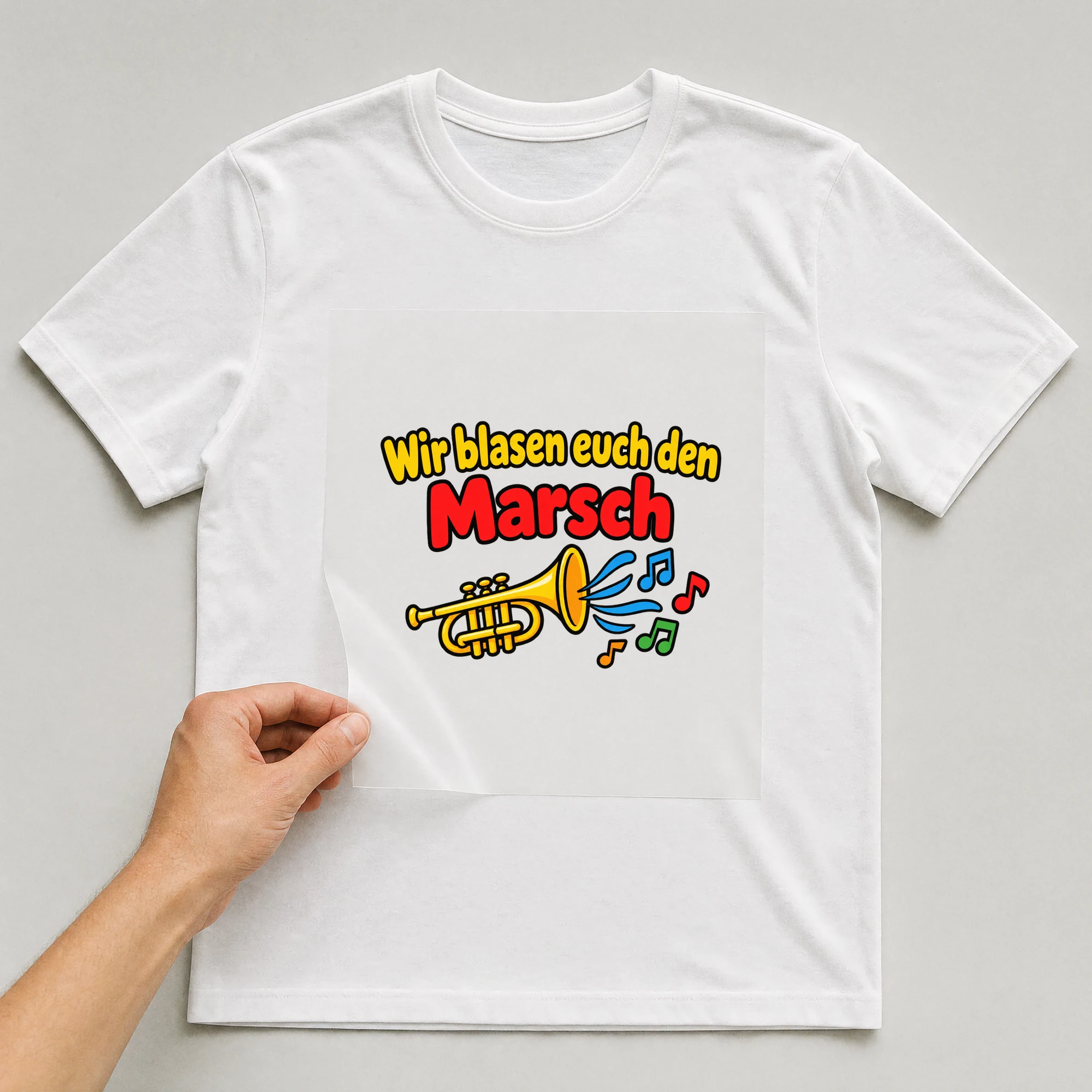 Bügelbild „Wir blasen euch den Marsch“ auf weißem T-Shirt, Folie wird aufgelegt