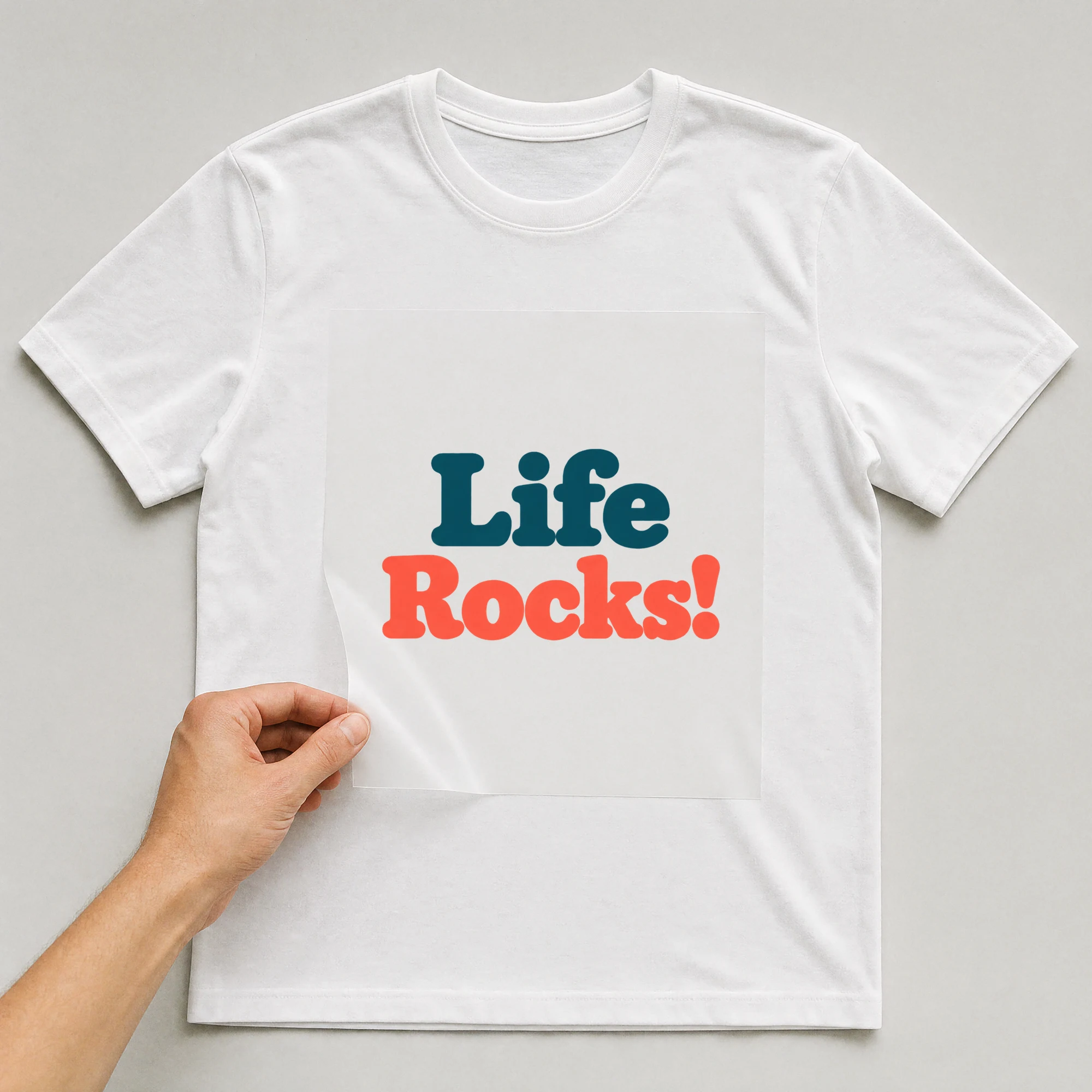 Bügelbild „Life Rocks!“ auf weißem T-Shirt, Folie wird aufgelegt