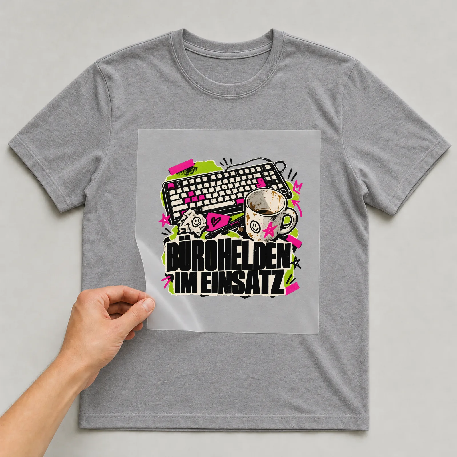 Bügelbild „Bürohelden im Einsatz“ auf grauem T-Shirt, Folie wird aufgelegt