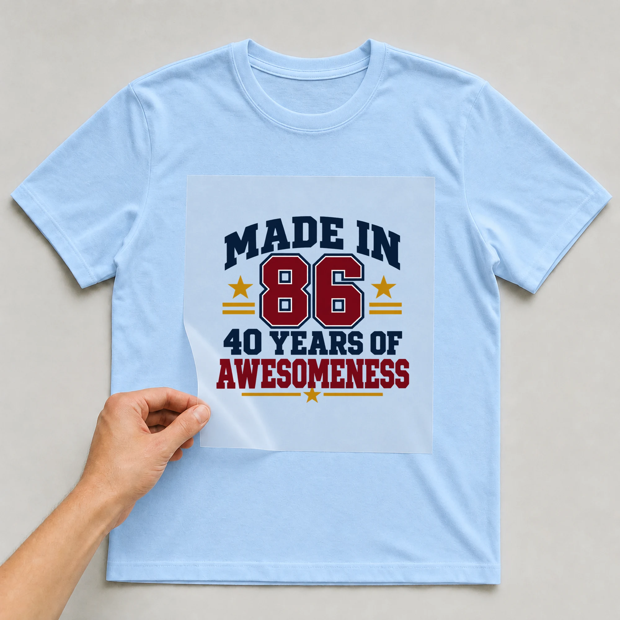 Bügelbild „Made In 86 40 Years Of Awesomeness“ auf babyblauem T-Shirt, Folie wird aufgelegt