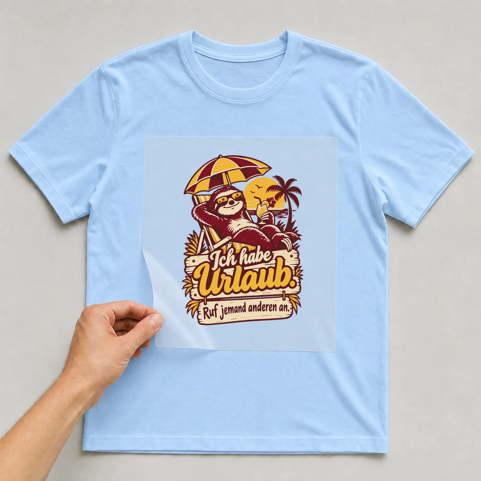 Bügelbild Ich habe Urlaub. Ruf jemand anderen an. auf hellblauem T-Shirt, Folie wird aufgelegt