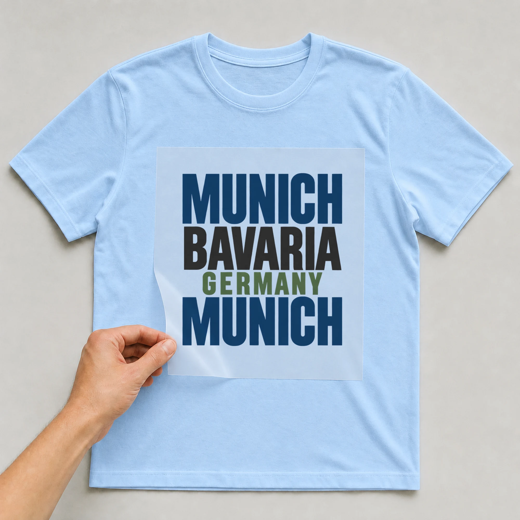 Bügelbild „Munich Bavaria Germany Munich“ auf babyblauem T-Shirt, Folie wird aufgelegt