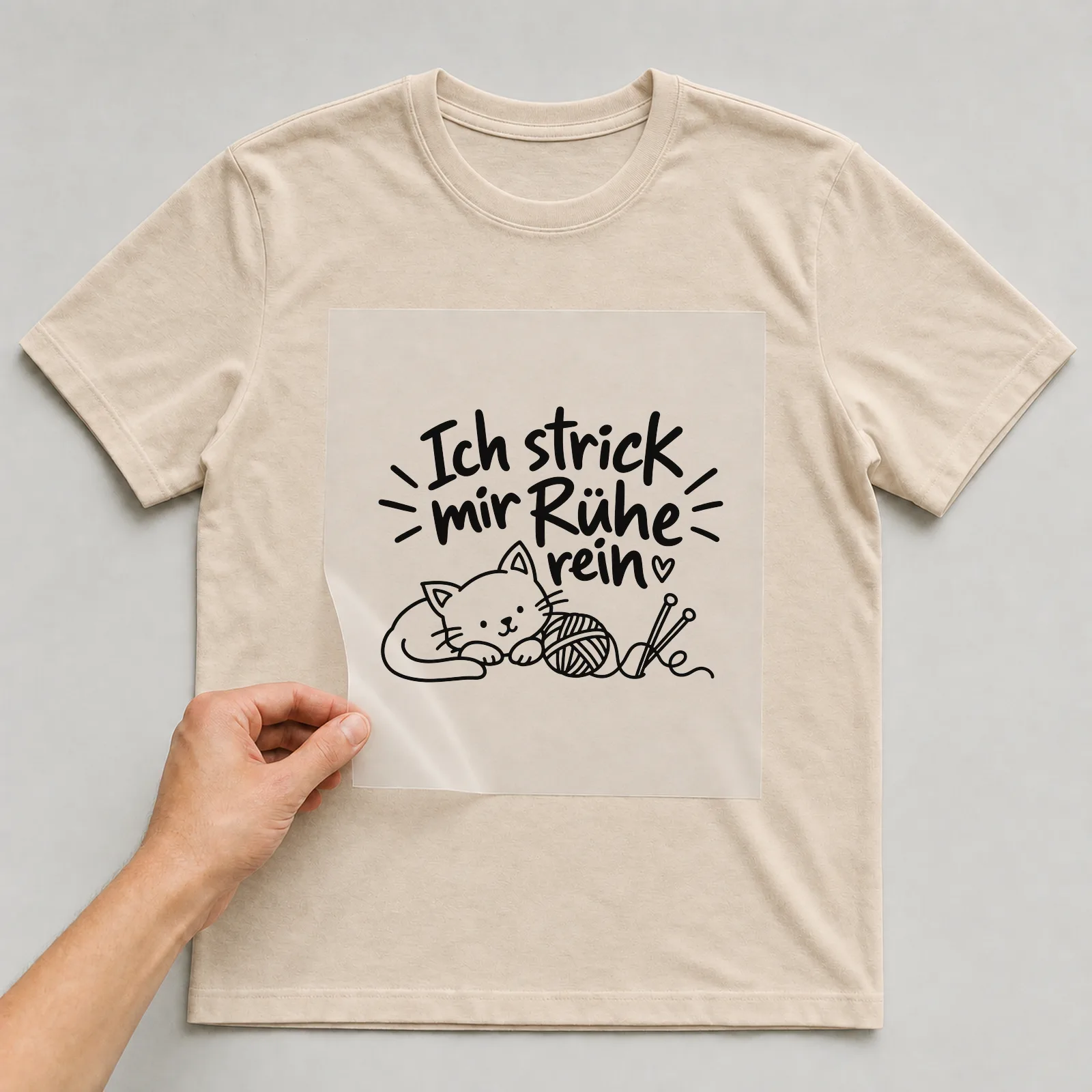 Bügelbild „Ich strick mir Ruhe rein“ auf beigem T-Shirt, Folie wird aufgelegt