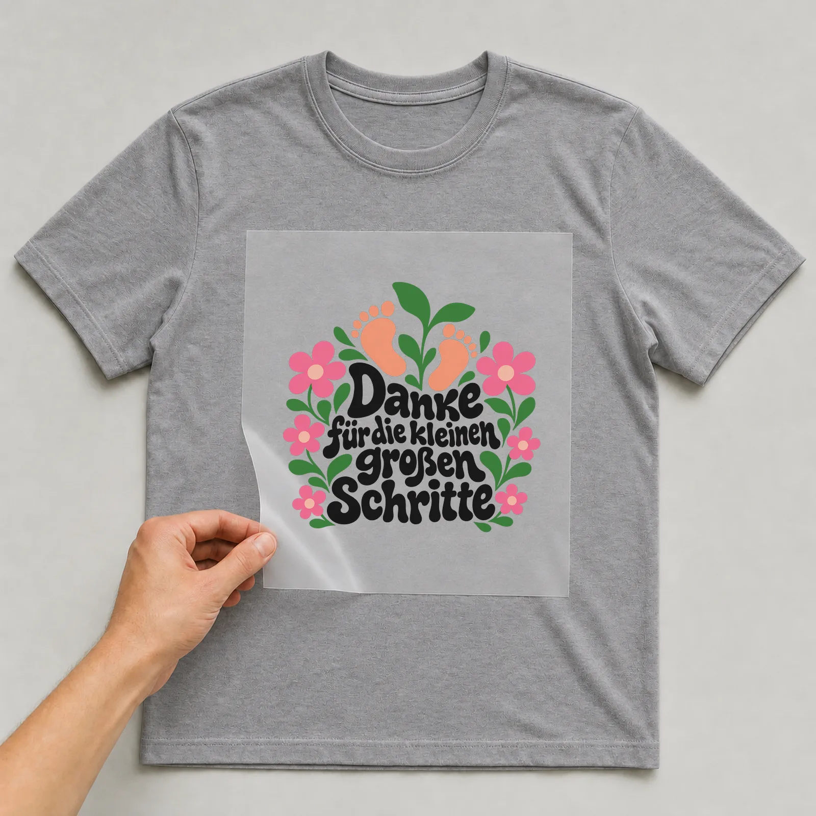 Bügelbild „Danke für die kleinen großen Schritte“ auf grauem T-Shirt, Folie wird aufgelegt