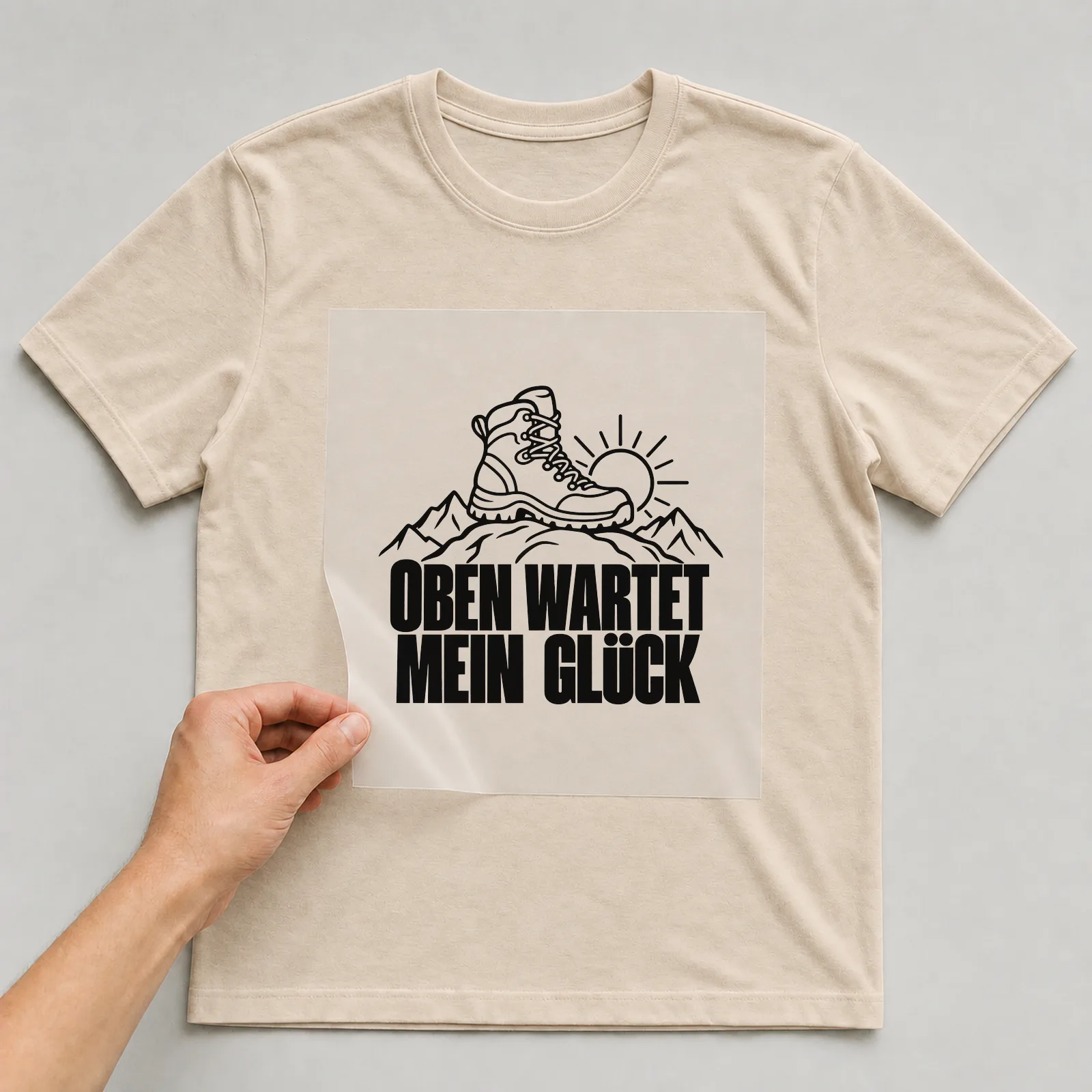 Bügelbild „Oben wartet mein Glück“ auf beigem T-Shirt, Folie wird aufgelegt
