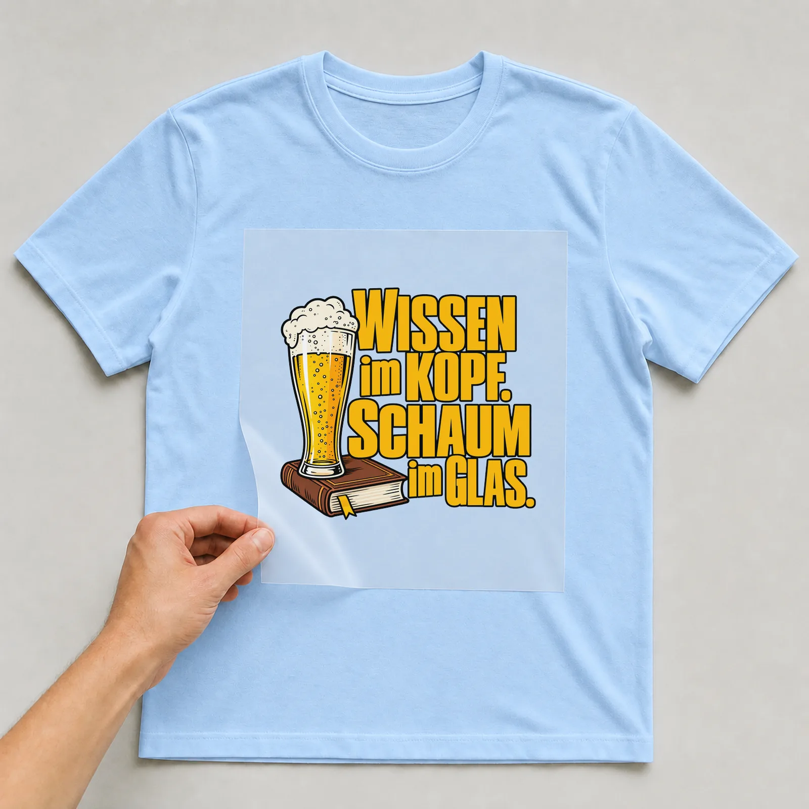 Bügelbild „Wissen im Kopf. Schaum im Glas.“ auf hellblauem T-Shirt, Folie wird aufgelegt