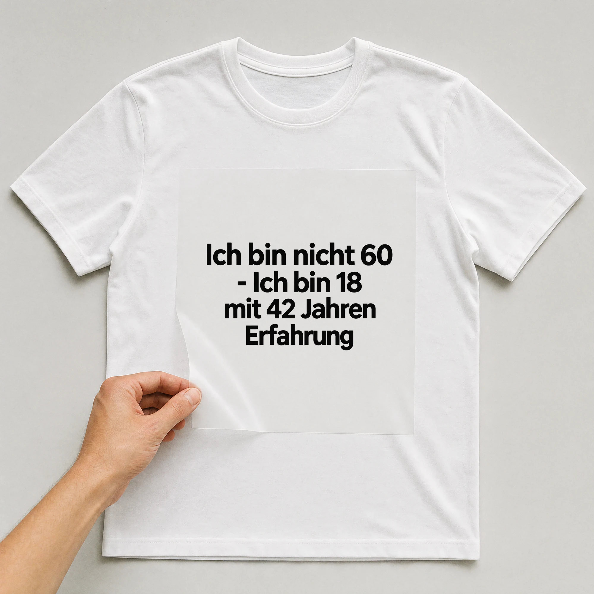 Bügelbild „Ich bin nicht 60 - Ich bin 18 mit 42 Jahren Erfahrung“ auf weißem T-Shirt, Folie wird aufgelegt