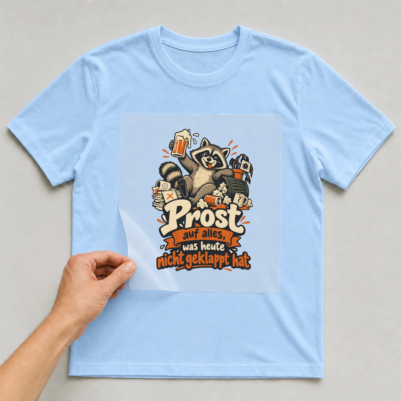 Bügelbild Prost auf alles, was heute nicht geklappt hat auf hellblauem T-Shirt, Folie wird aufgelegt