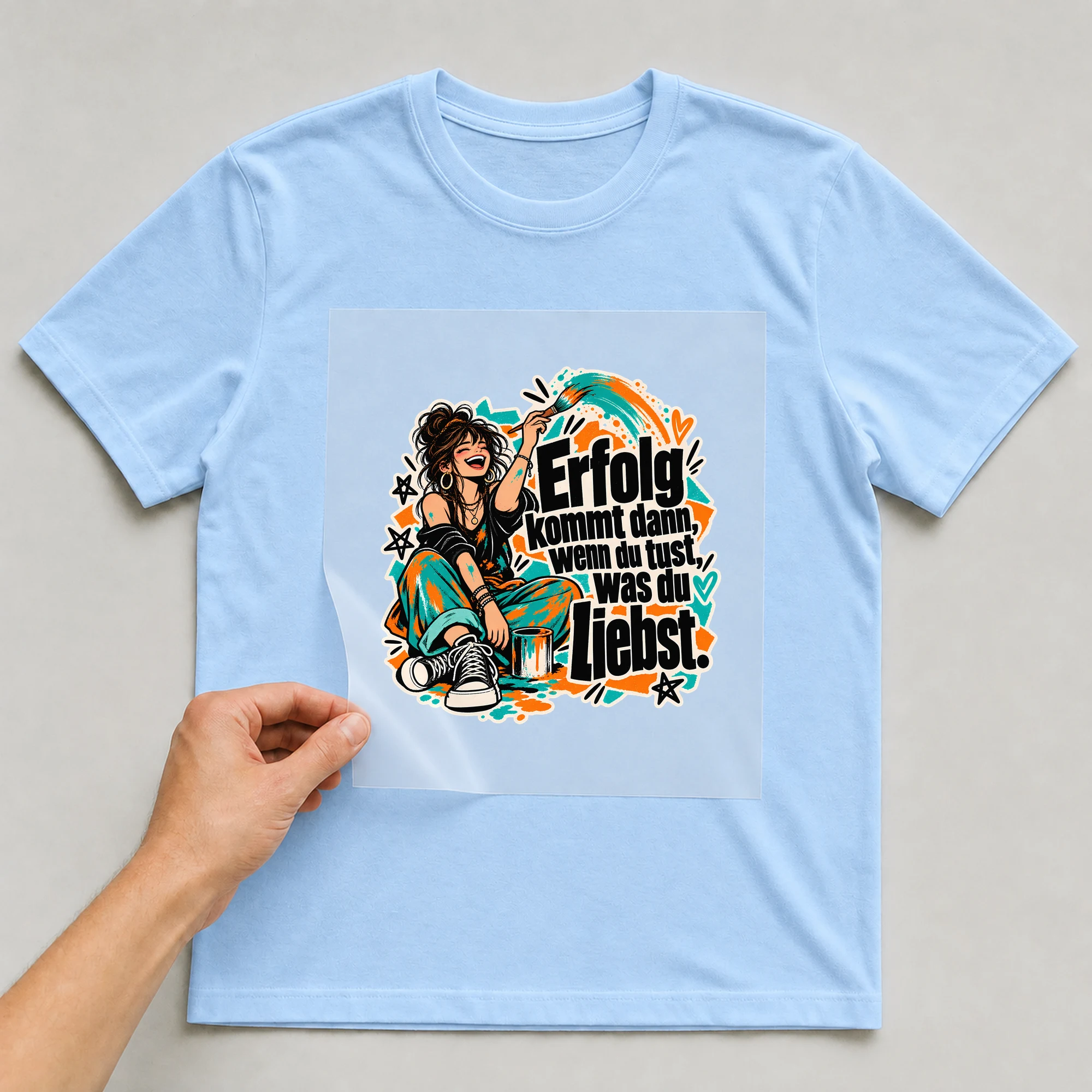 Bügelbild „Erfolg kommt dann, wenn du tust, was du liebst.“ auf babyblauem T-Shirt, Folie wird aufgelegt