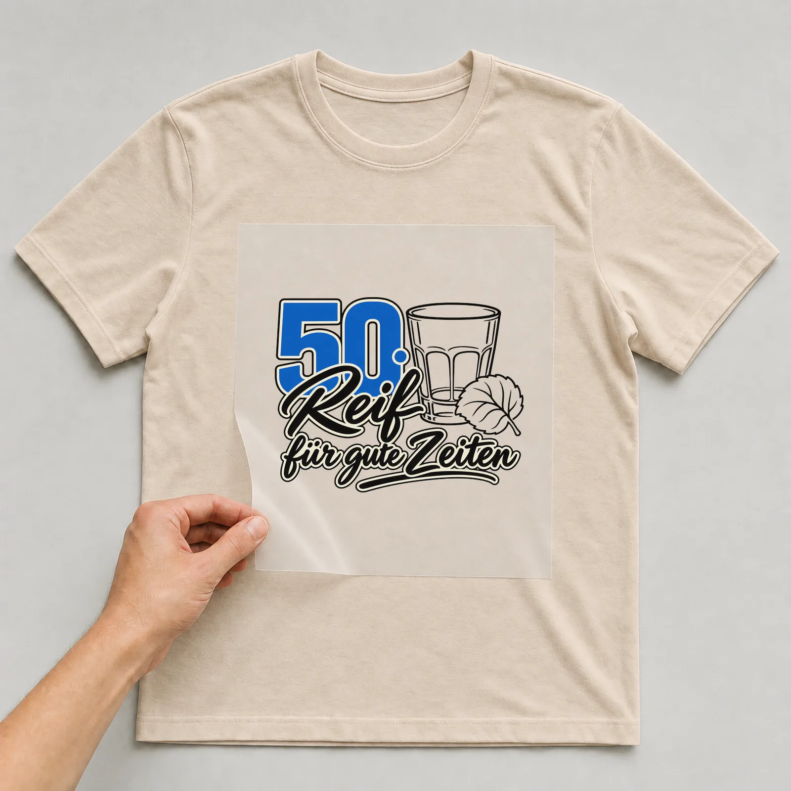 Bügelbild „50 · Reif für gute Zeiten“ auf beigem T-Shirt, Folie wird aufgelegt