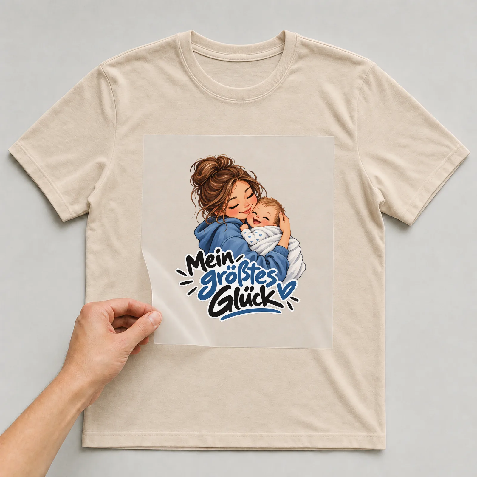 Bügelbild „Mein größtes Glück“ auf beigem T-Shirt, Folie wird aufgelegt